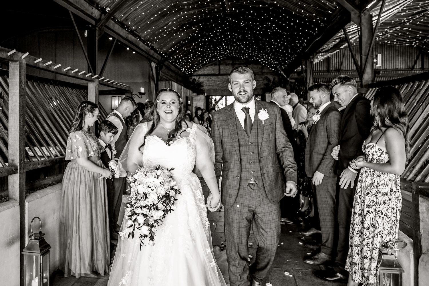 Bride and Groom leaving the ceremony with confetti thrown over them Stone Barn Wedding Venue Cheltenham The Cotswolds