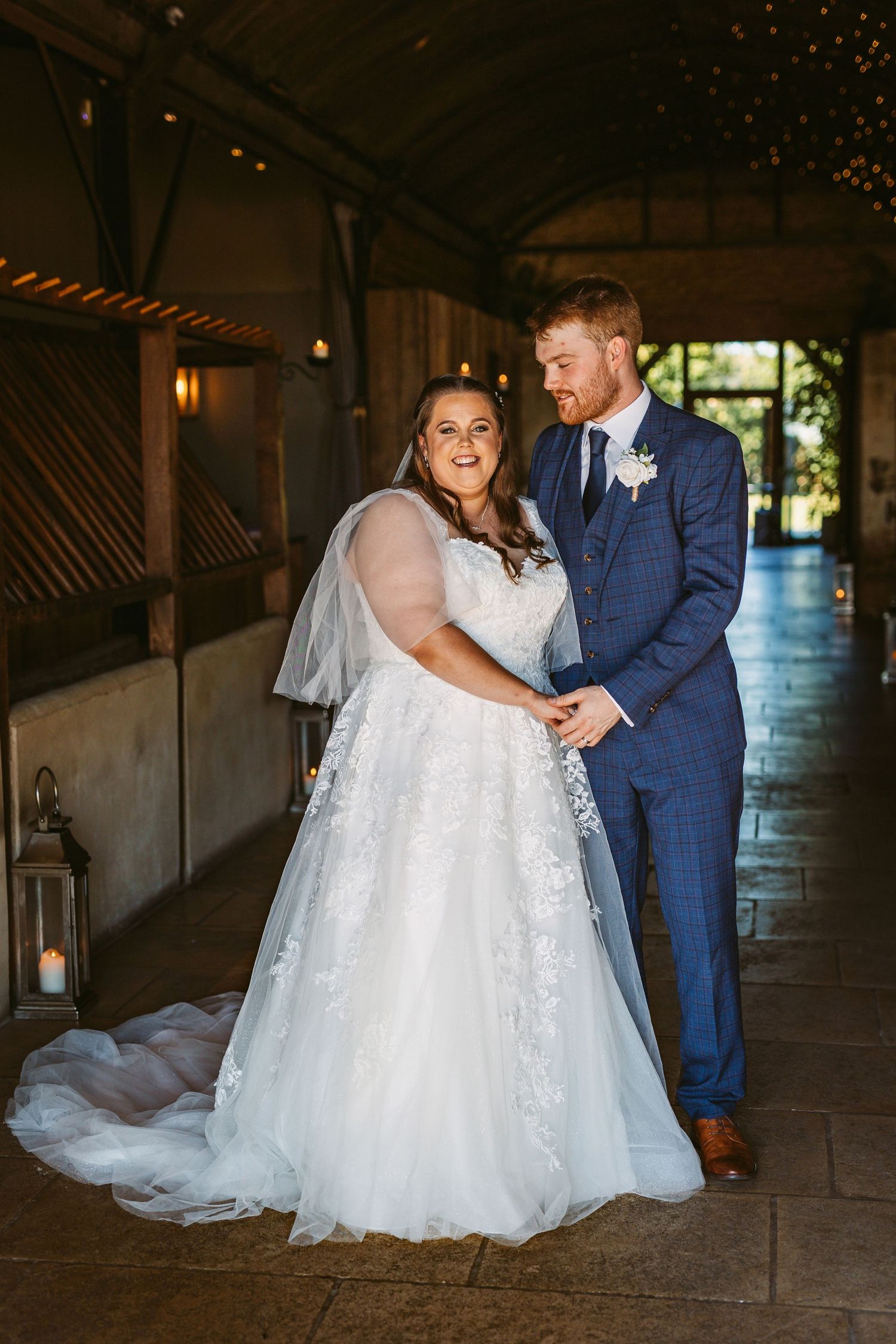 Bride and Groom portrait of beautiful couple standing in Stone Barn with pretty lights
