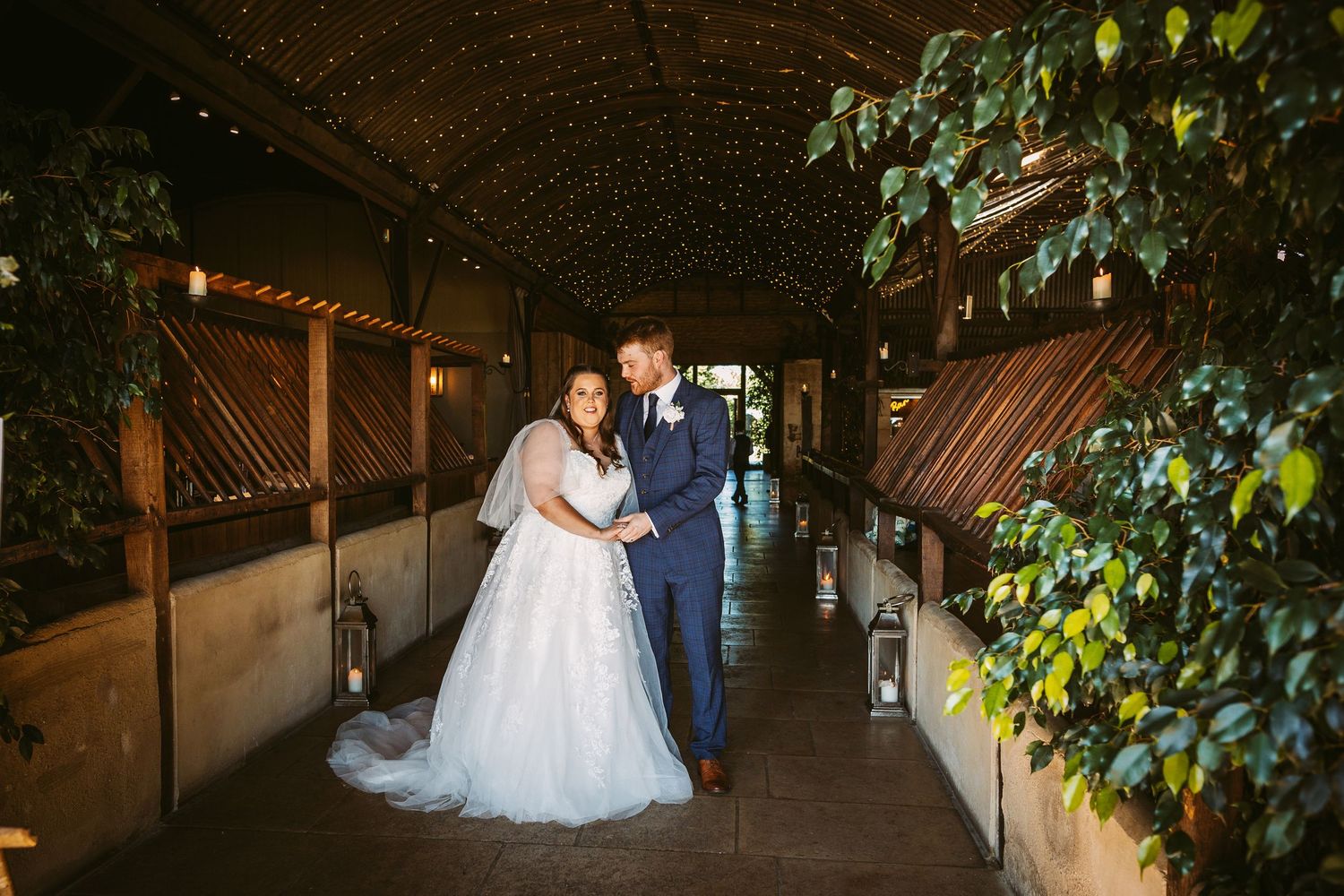 Bride and Groom portrait of beautiful couple standing in Stone Barn with pretty lights