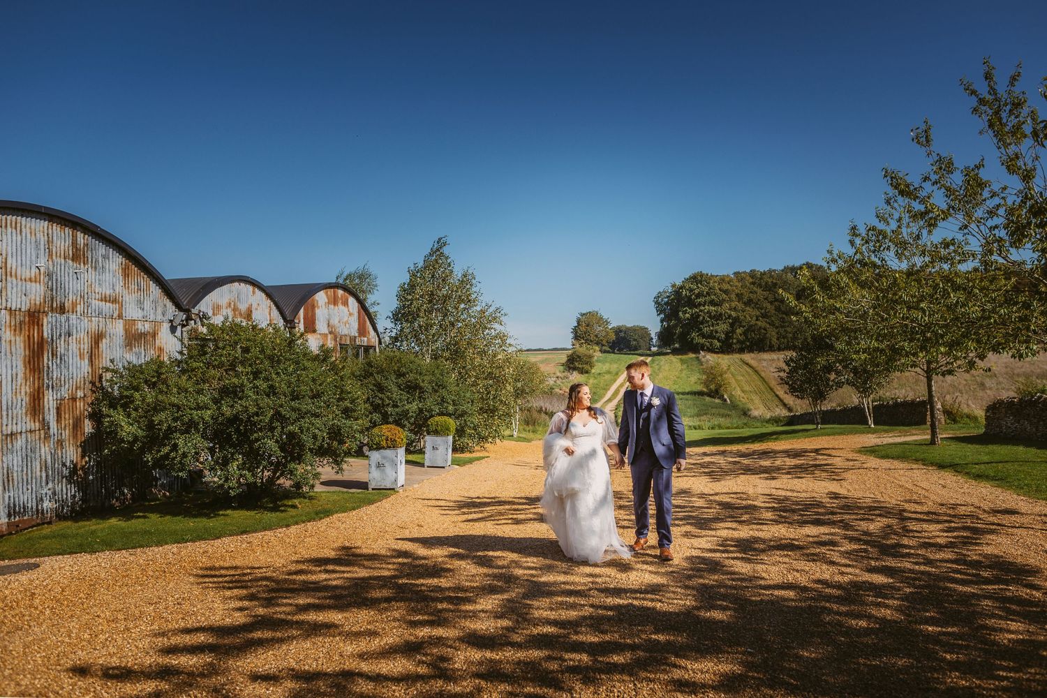 Bride and Groom portrait of beautiful couple walking Stone Barn blue sky