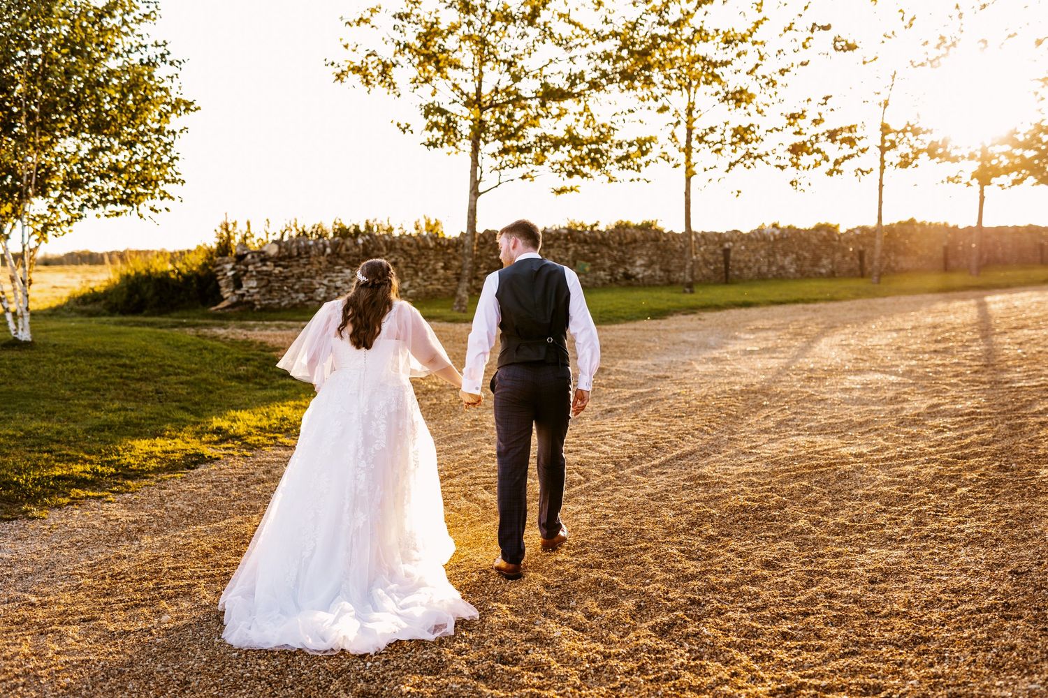 Bride and Groom walking in golden hour sunset Stone Barn The Cotswolds