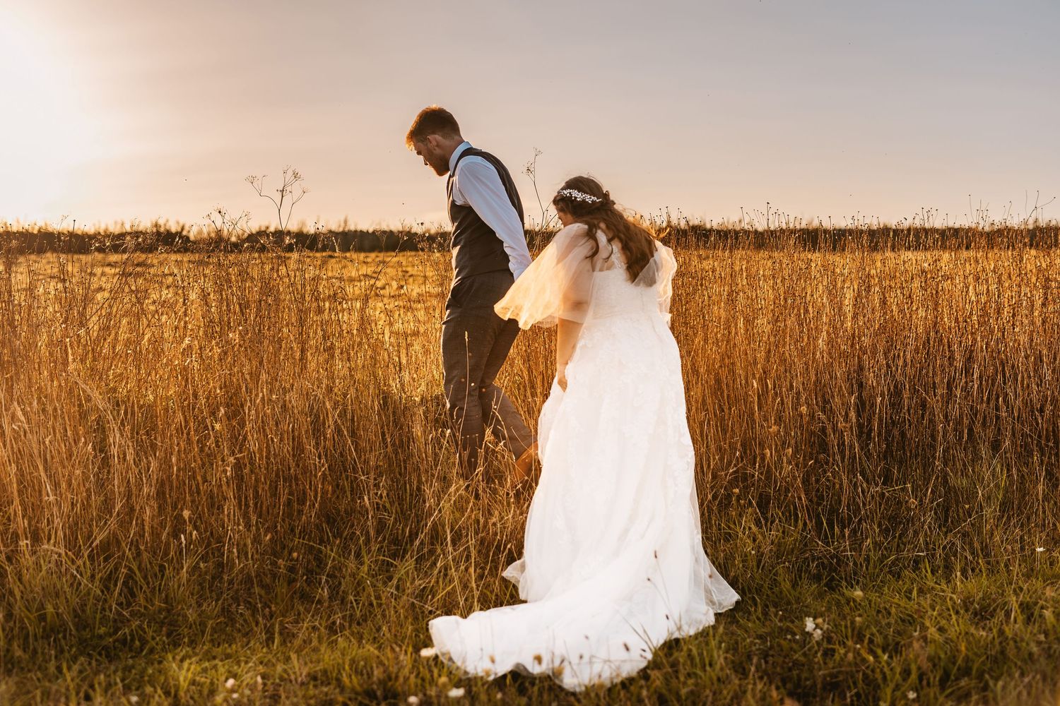 Groom leading bride into golden hour sunset Stone Barn The Cotswolds looks like film painting
