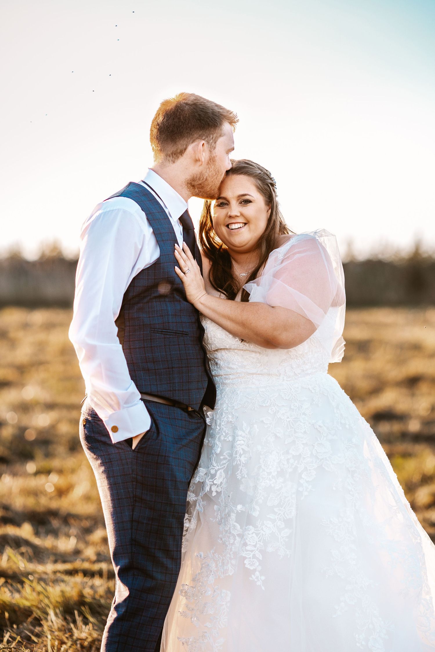 Groom kissing bride in golden hour sunset Stone Barn The Cotswolds