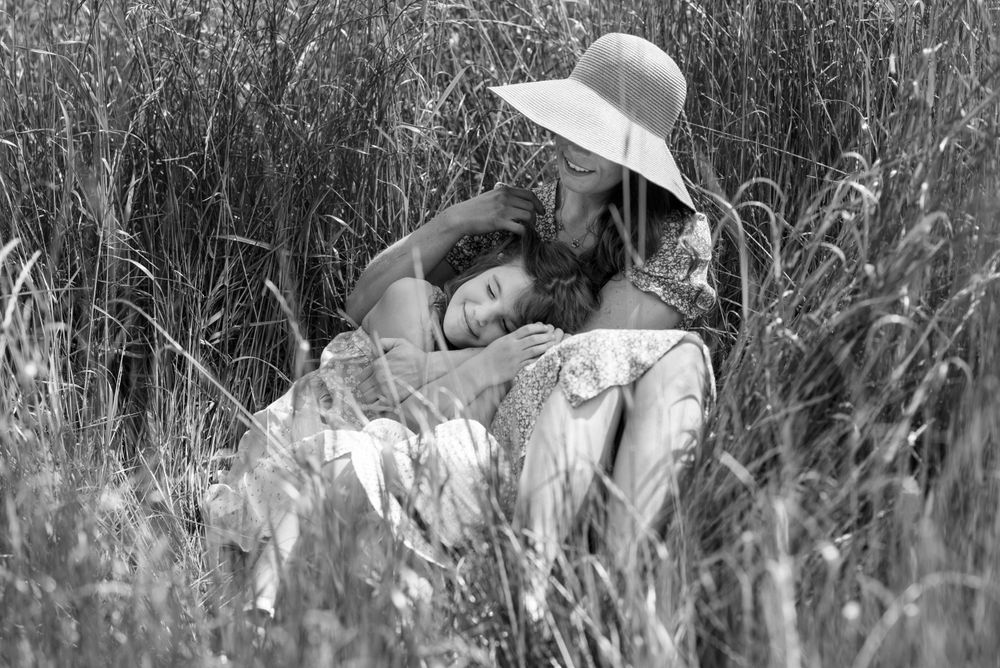 Ethereal photographs of people resting in tall grass during golden hour.