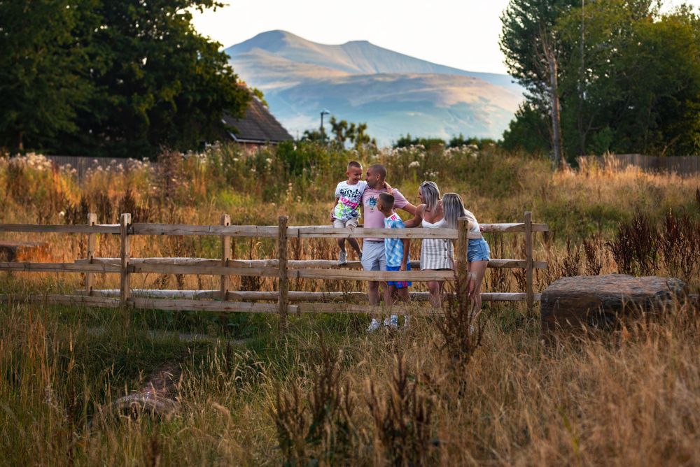 Mountain landscape view with rustic wooden fencing and tall grass in foreground.
