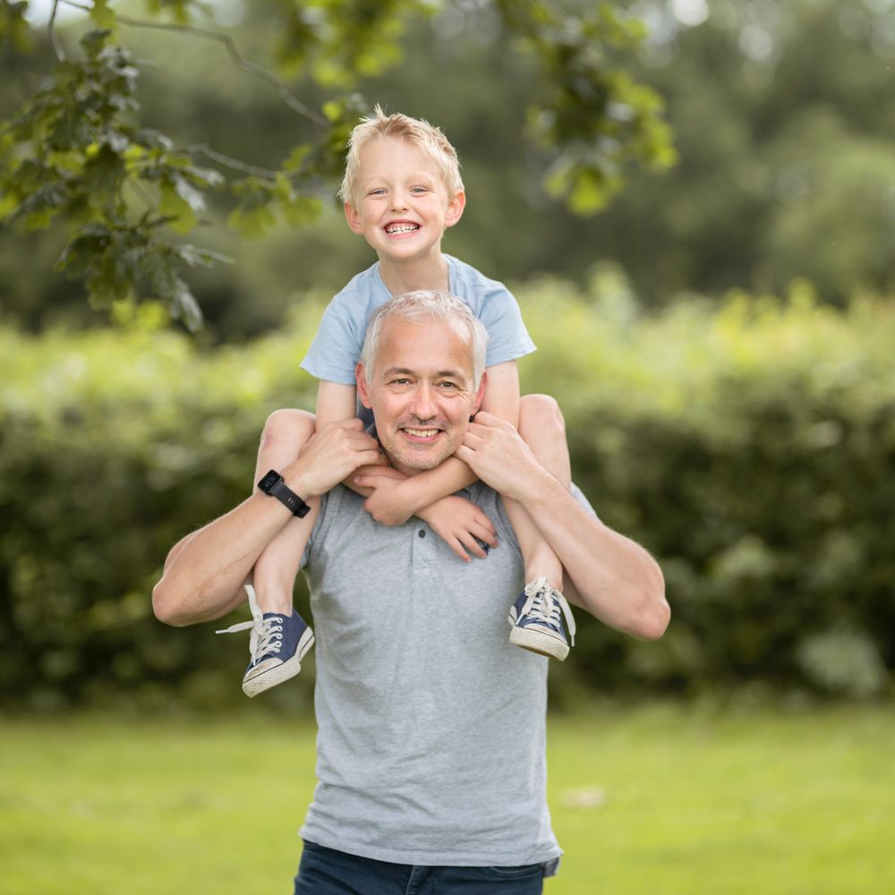 A playful sequence of piggyback rides in a lush green outdoor setting on a sunny day.