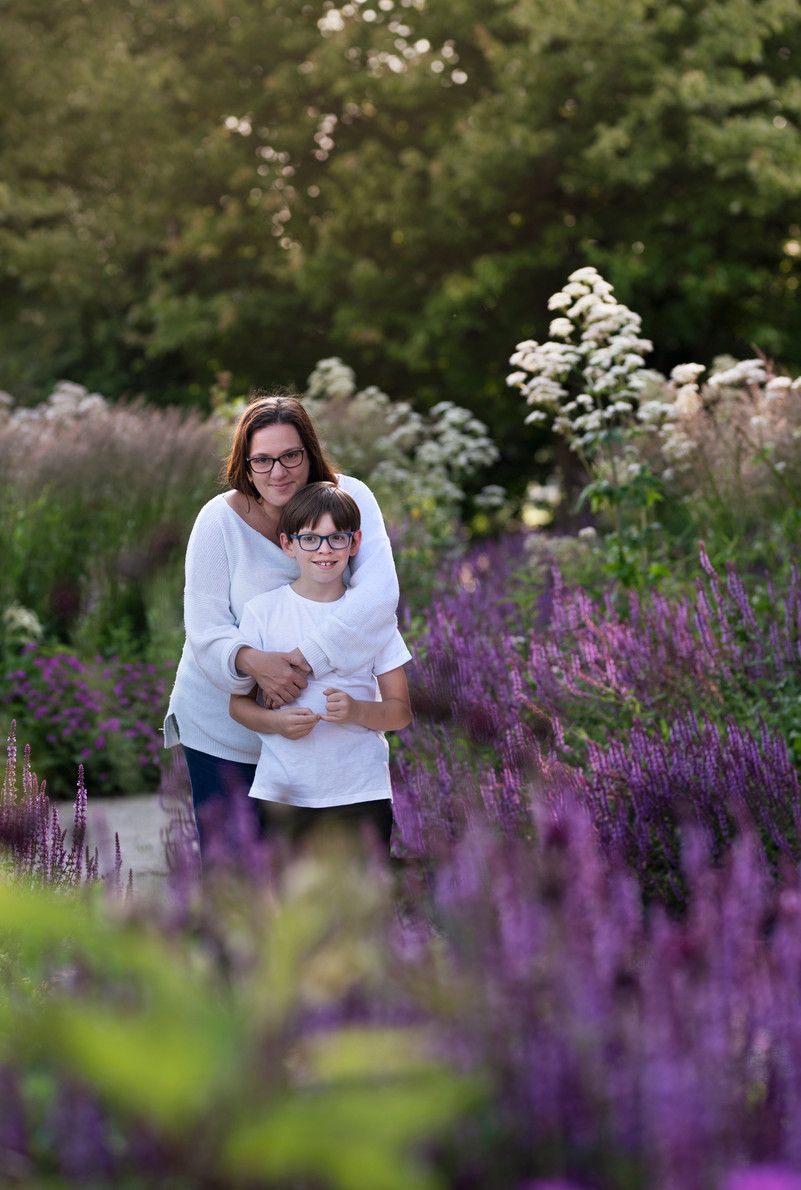 Two people sharing an embrace among blooming purple flowers in a garden.
