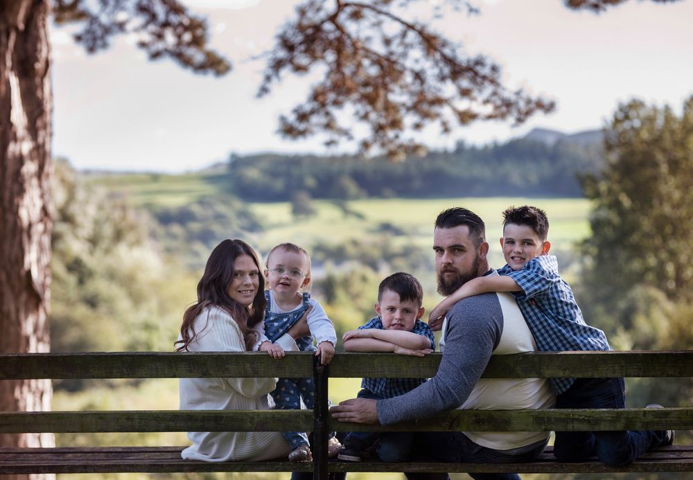 Family sitting together on a wooden bench overlooking scenic countryside views.