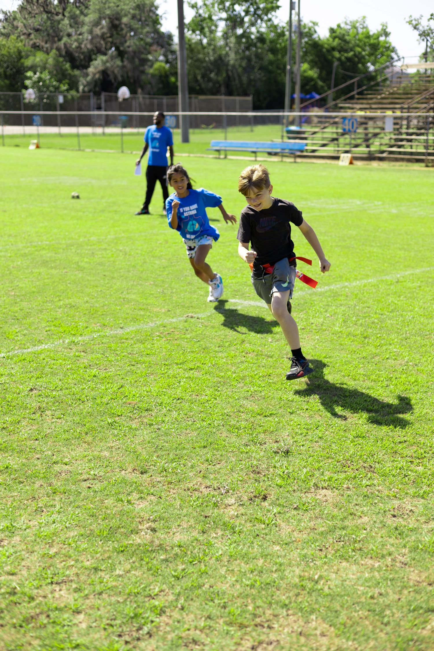 Children running together on a green sports field during an outdoor athletic activity.