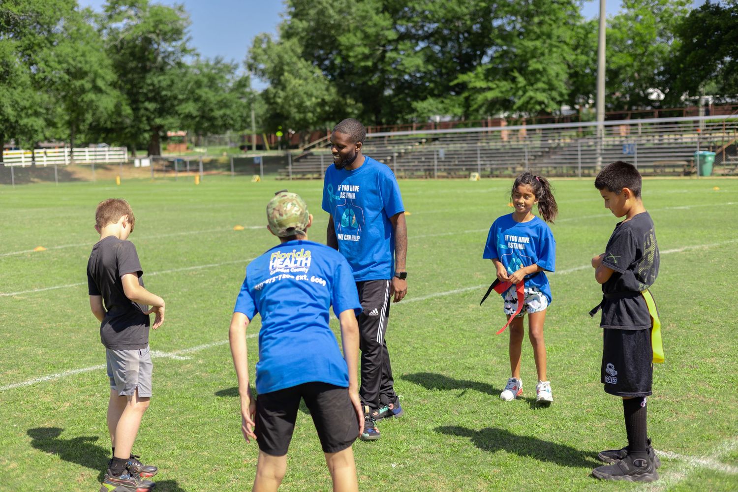 Kids participating in outdoor sports training activities with coaches at a sunny field.