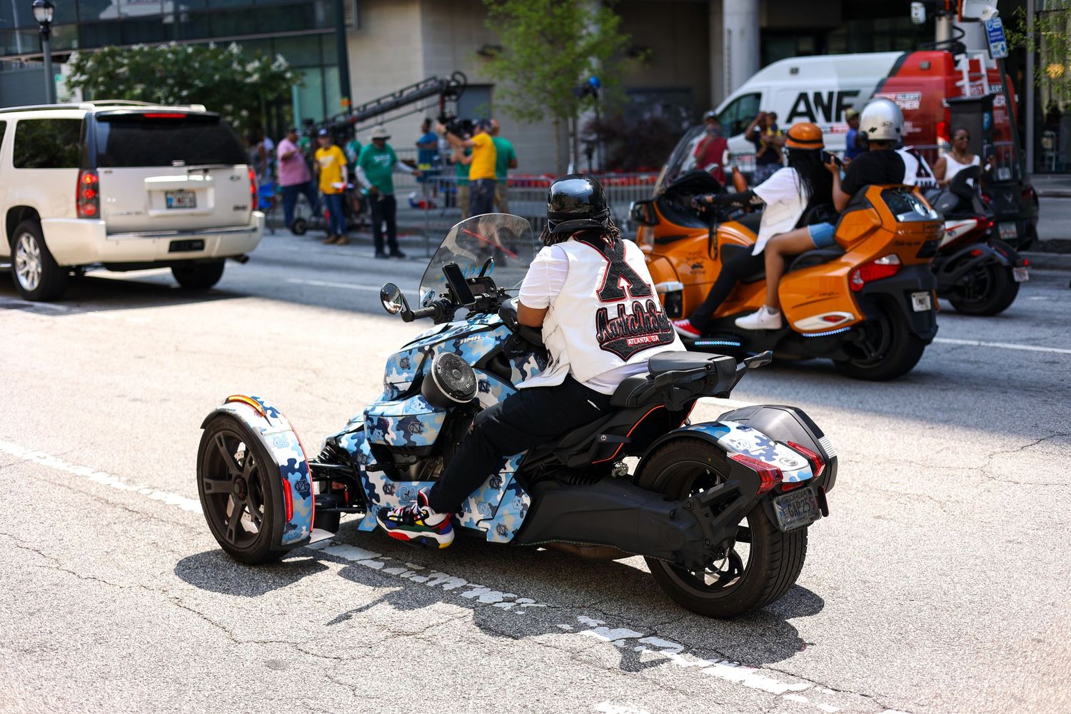 A line of custom motorcycles and trikes parked on a city street during an event.
