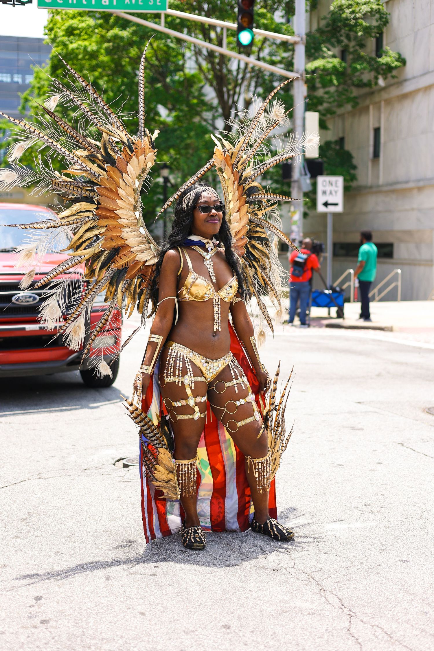 Person wearing an elaborate golden feathered carnival costume on a city street.