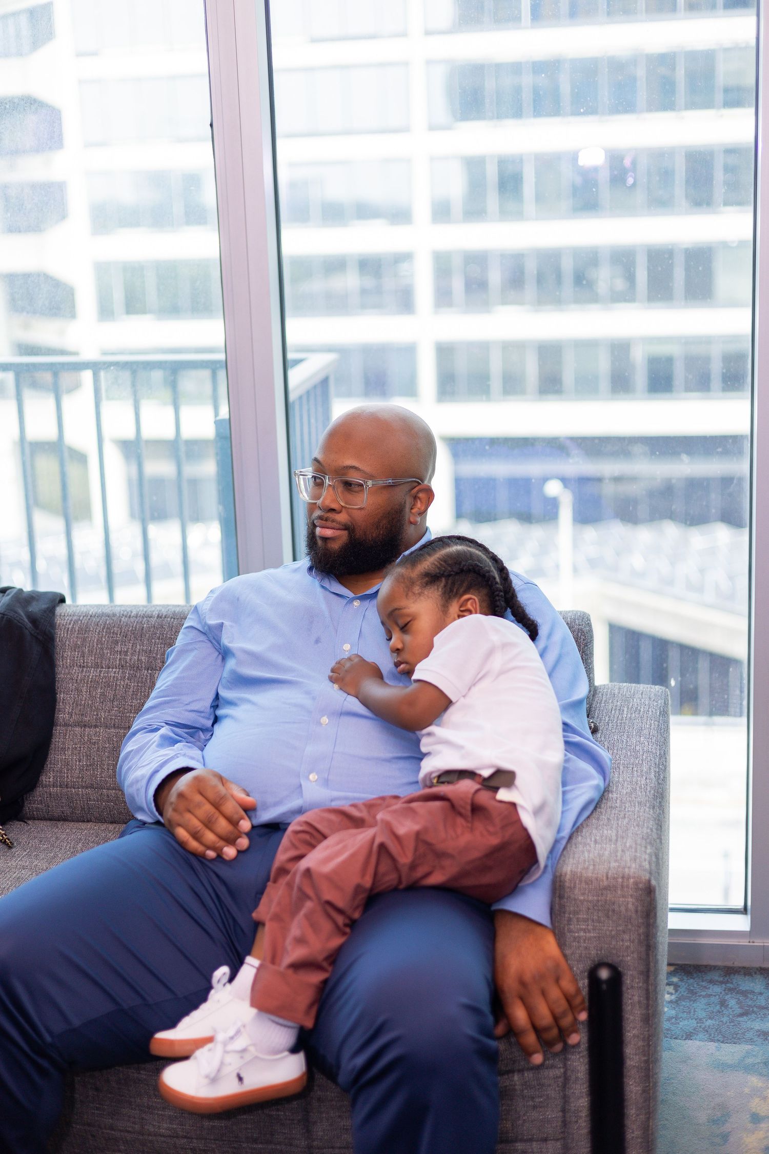 A quiet moment of rest on a couch near a window overlooking city buildings.