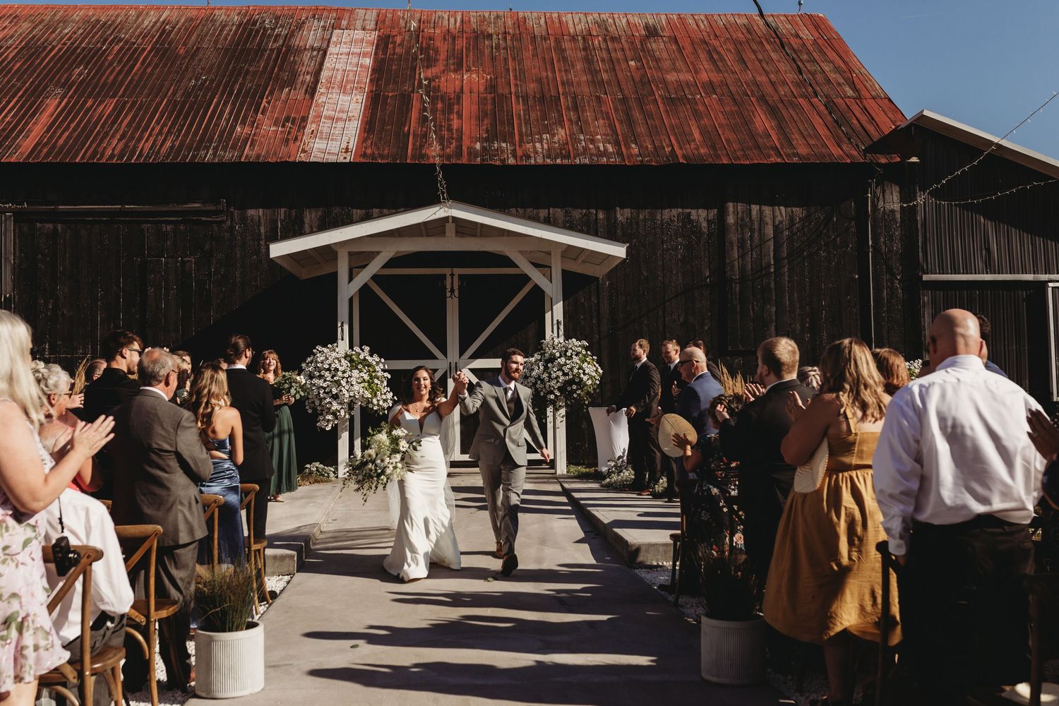 Wedding ceremony exit at a rustic barn venue with guests lining the aisle with sparklers.