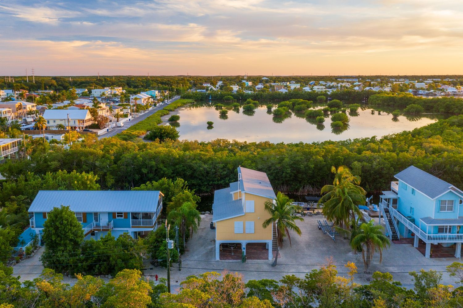 Scenic sunset view of a coastal community with houses and waterways stretching into the horizon.