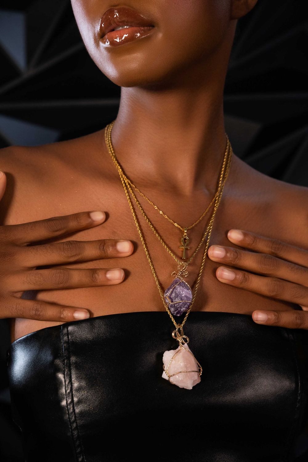 Close up of neck adorned with layered gold necklaces featuring crystal pendants.