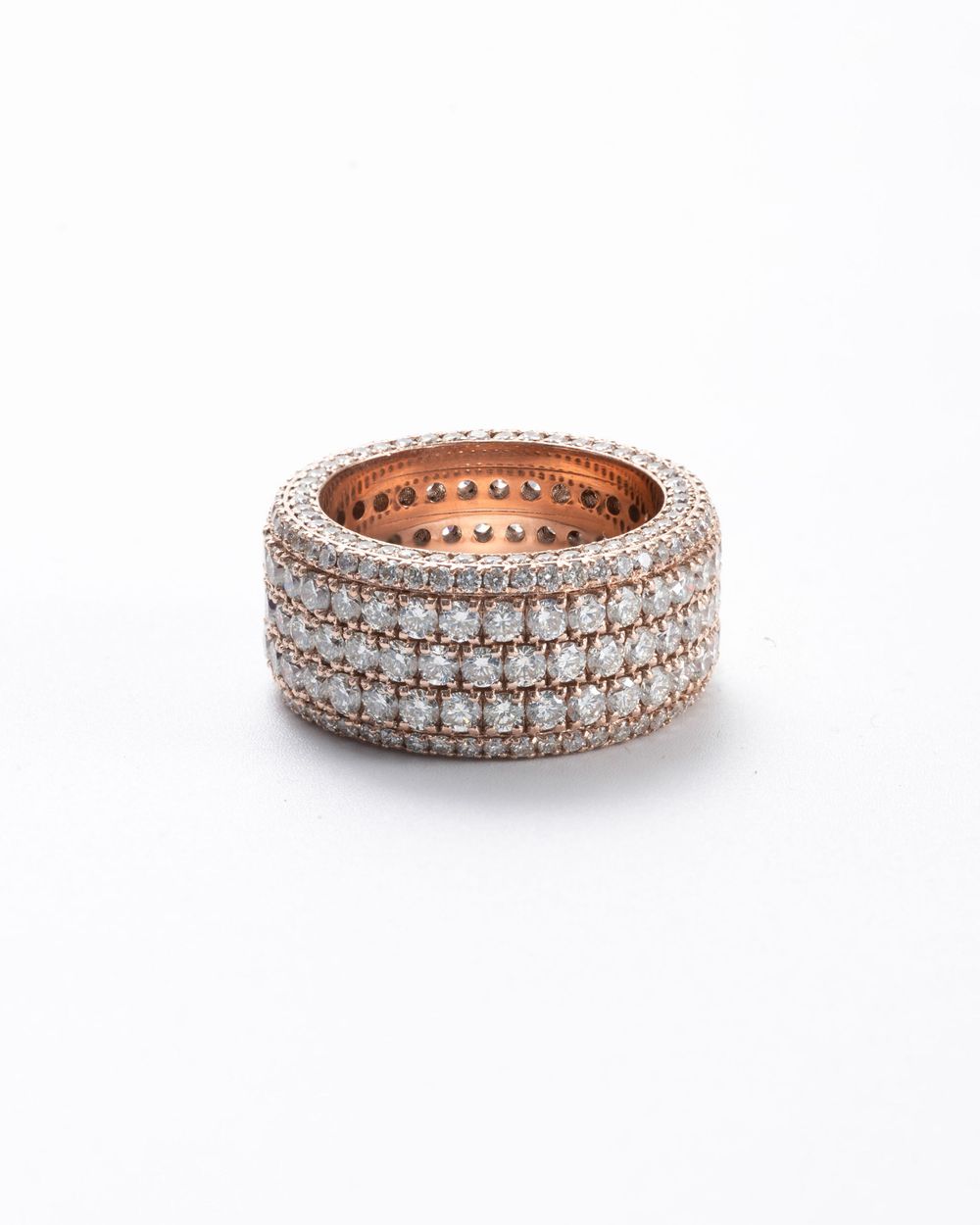 Rose gold eternity ring with multiple rows of pave diamonds on white background.