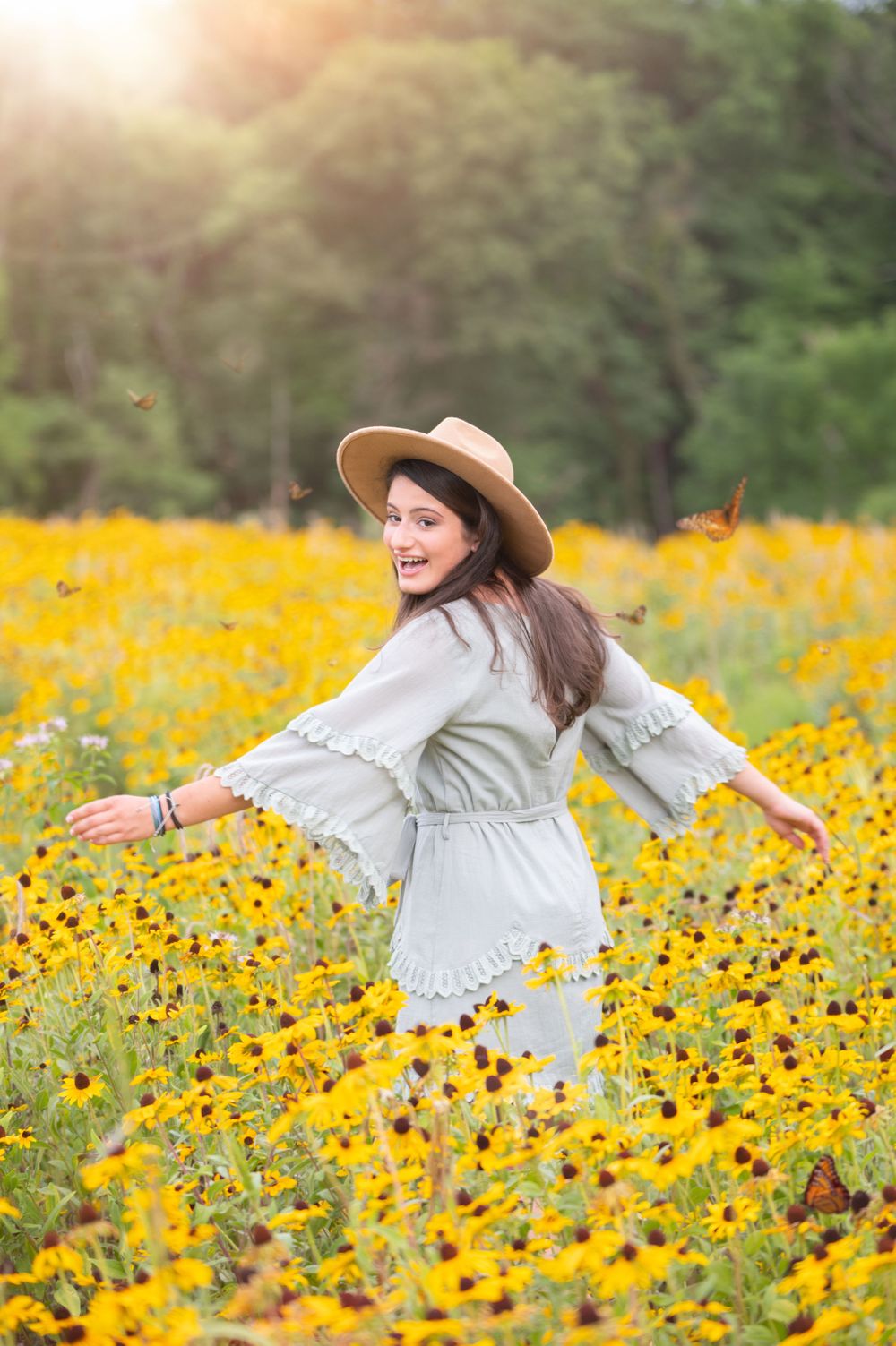 Someone twirling joyfully in a white dress in a field of yellow wildflowers.