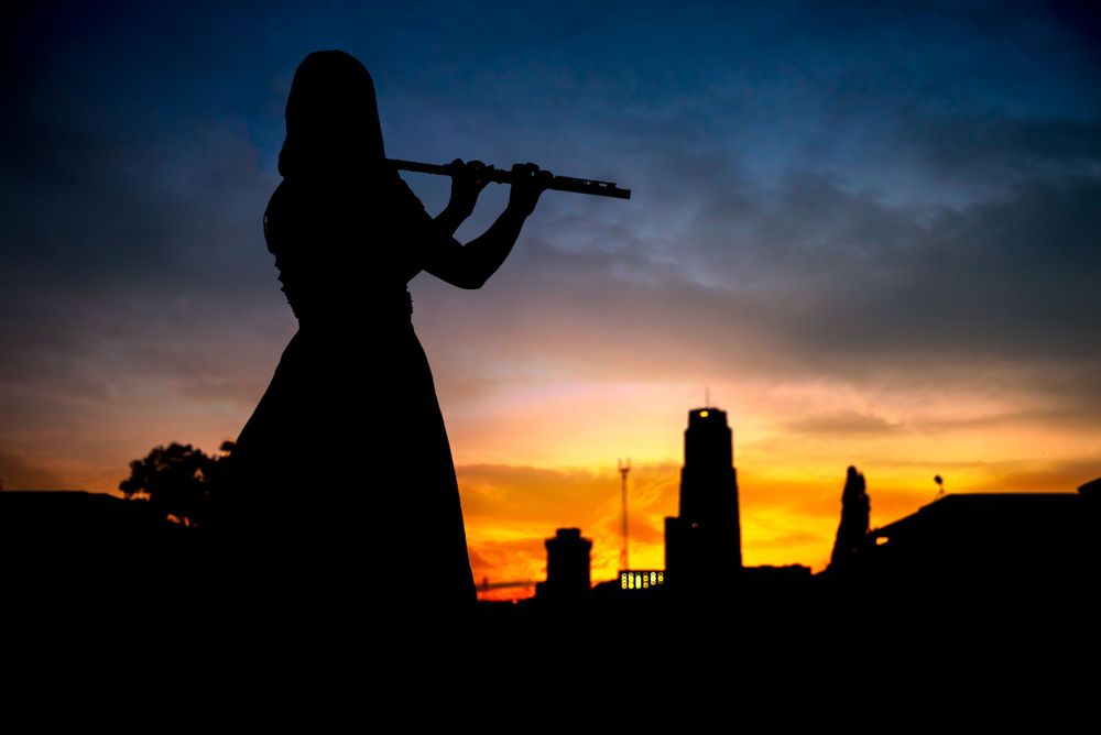 Silhouette of a violin player against a dramatic sunset sky.