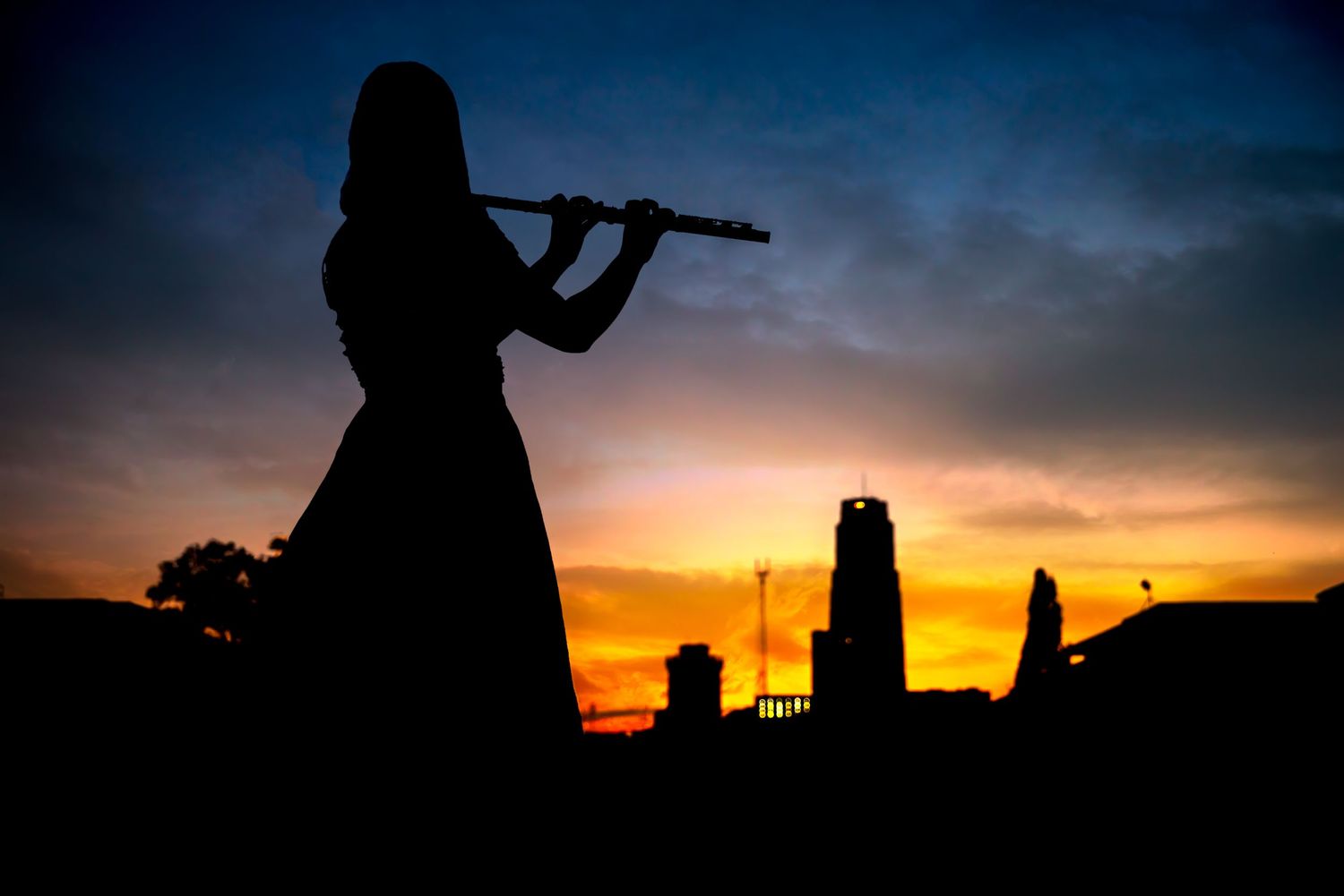 Silhouette of a violin player against a dramatic sunset sky.