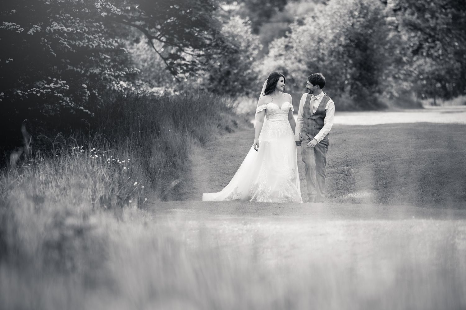 Black and white portrait of couple standing in dreamy meadow setting.