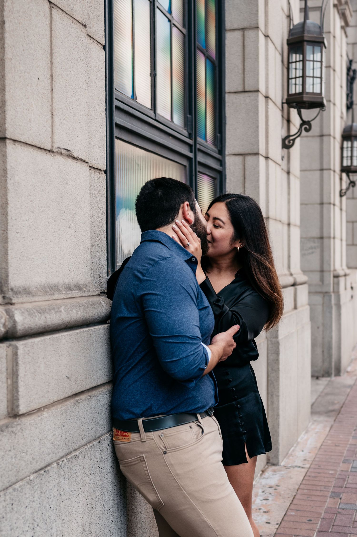 A romantic moment between a couple in front of an ornate building with vintage architecture.