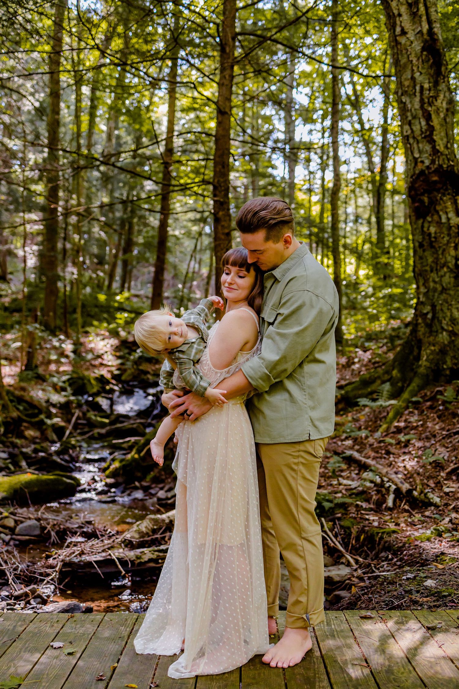 mom dad and baby brigde in woods