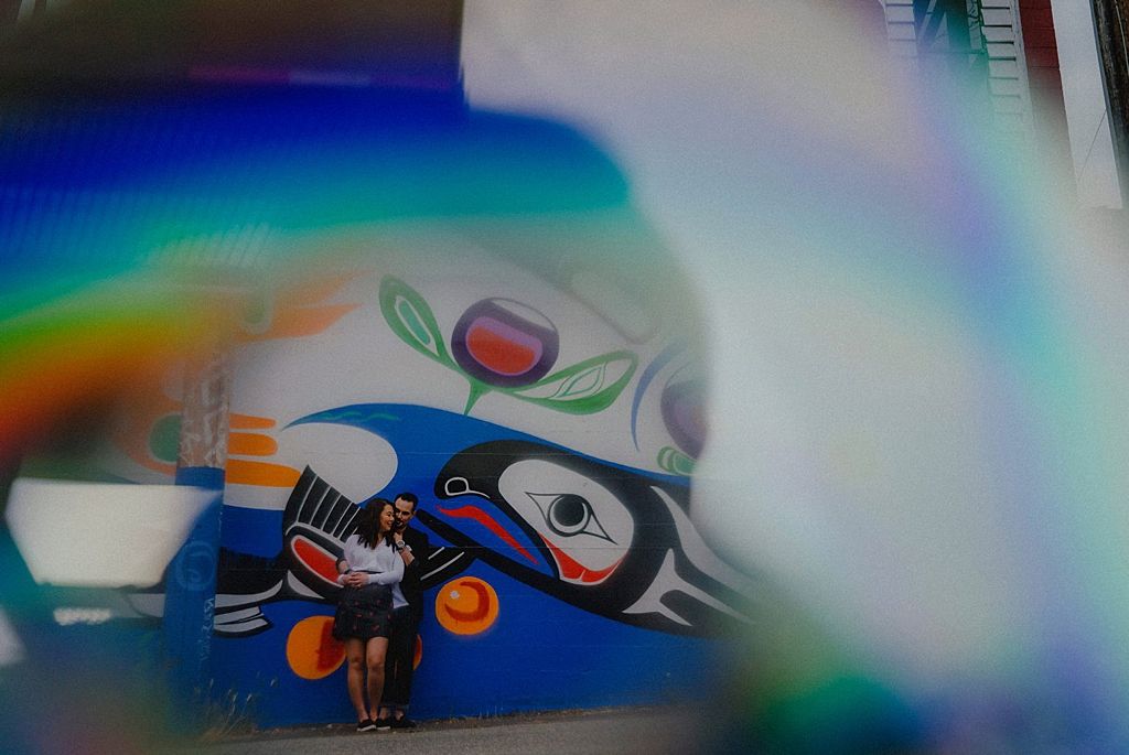 Abstract artistic photo with rainbow light effects and partial view of street art mural.