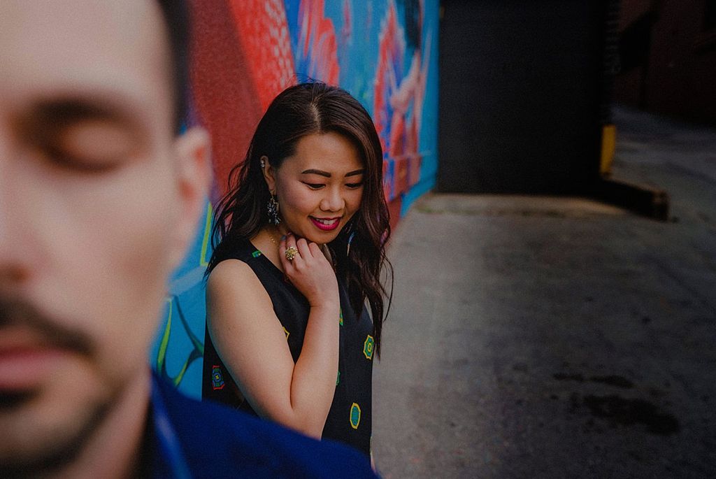 Playful couple posing against vibrant street art murals with bright blue walls.
