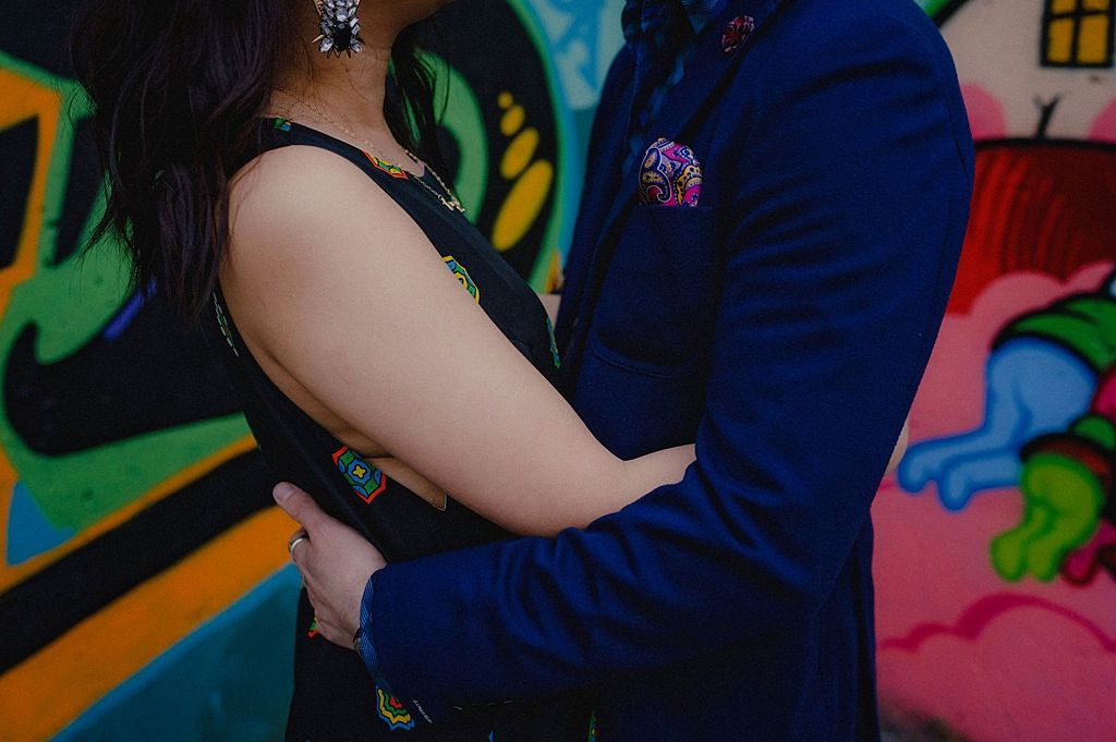 Close-up shot showing embrace against colorful graffiti wall background.