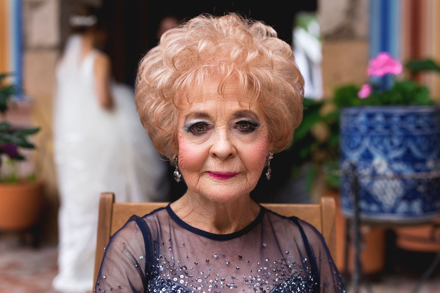 An elegant senior woman in a sparkly evening dress poses at a formal event.