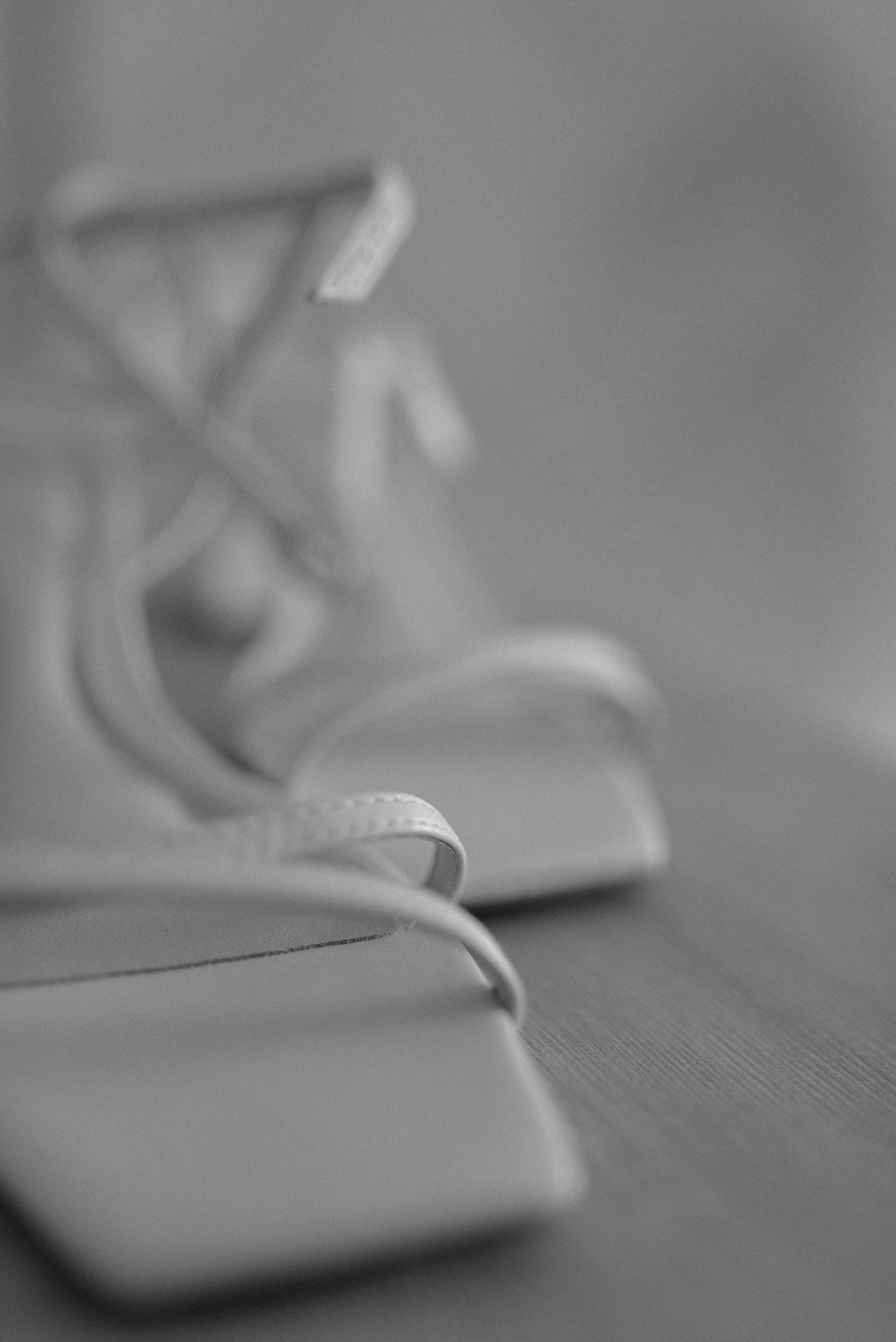 Artistic shallow focus shot of white bridal shoes on wooden surface.