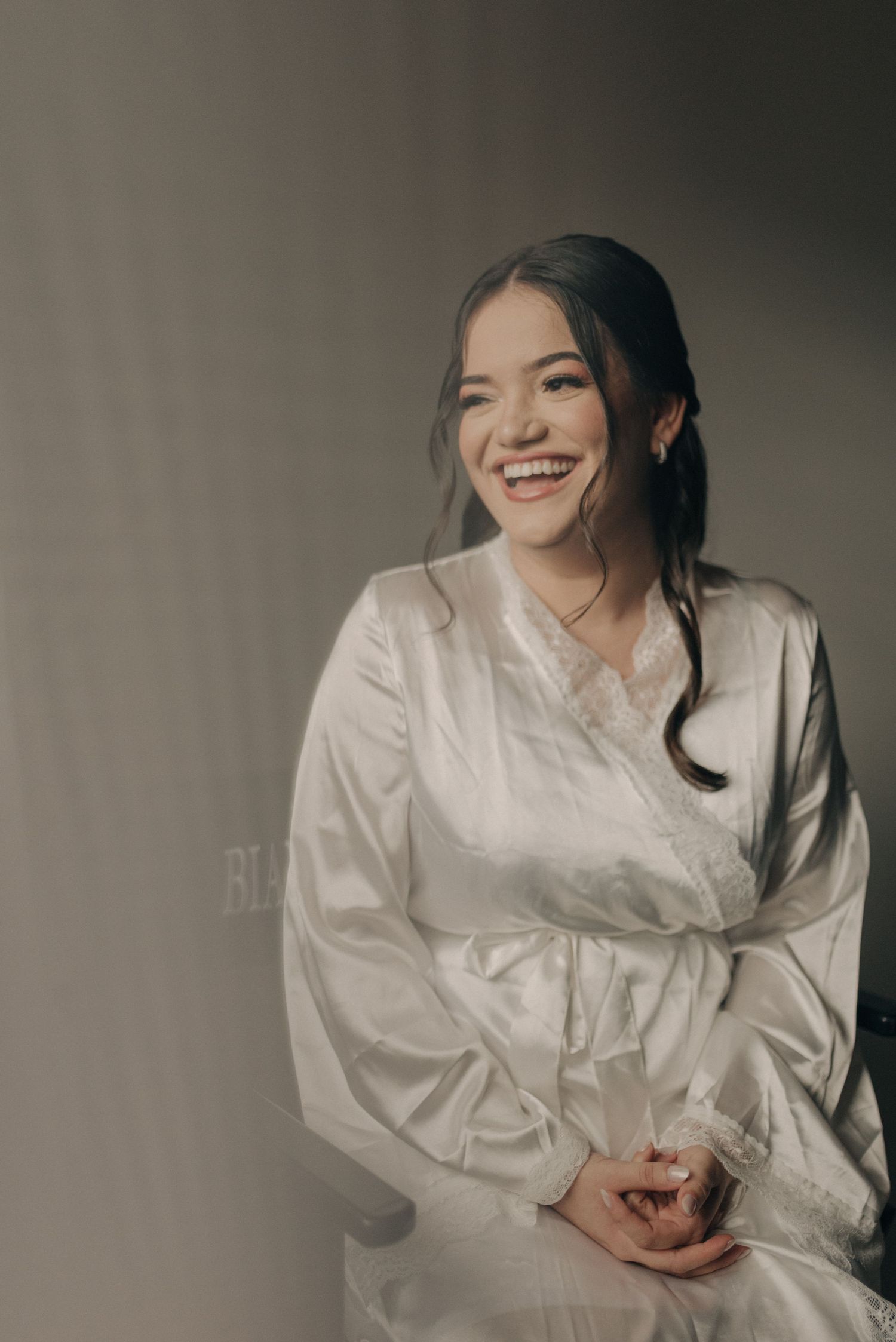 Portrait in a white silk robe with soft lighting against a neutral background.