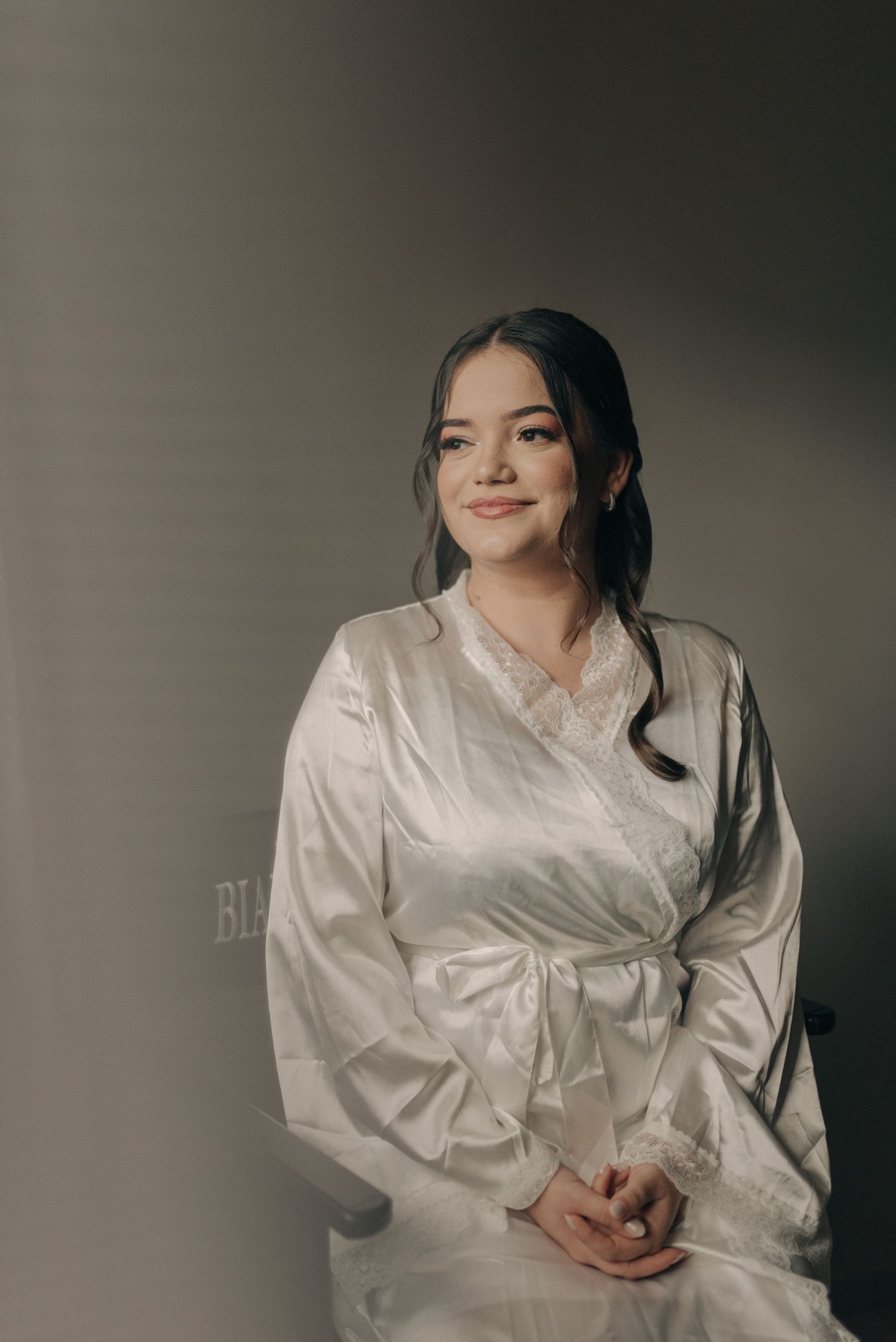 Elegant portrait in a white silk wrap robe against a minimal backdrop.