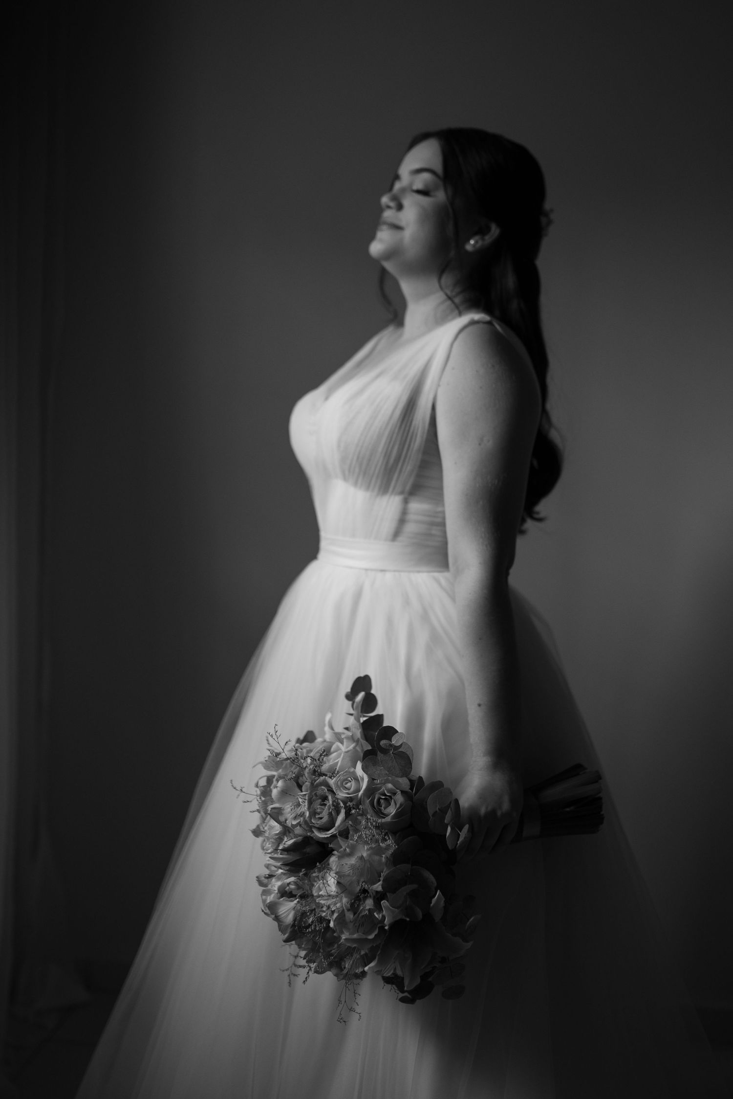 Dramatic black and white bridal portrait with a romantic bouquet and flowing ball gown.