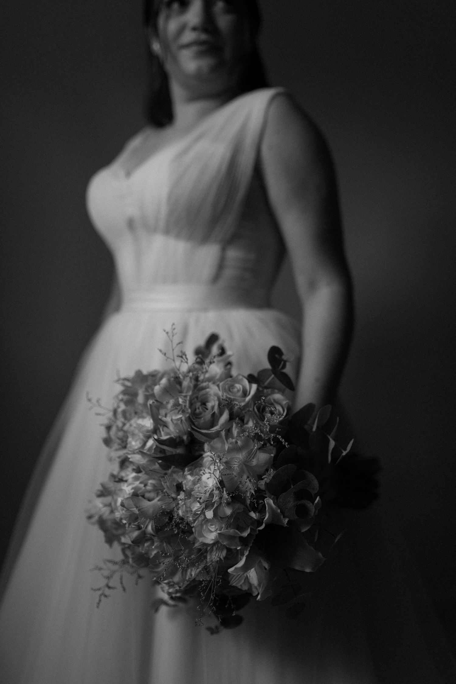 Black and white portrait of a bride in a classic ballgown holding a lush floral bouquet.