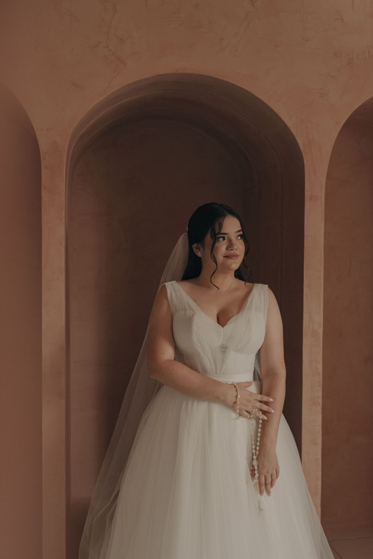 Bridal portrait showcasing a classic ballgown wedding dress against terracotta arches.