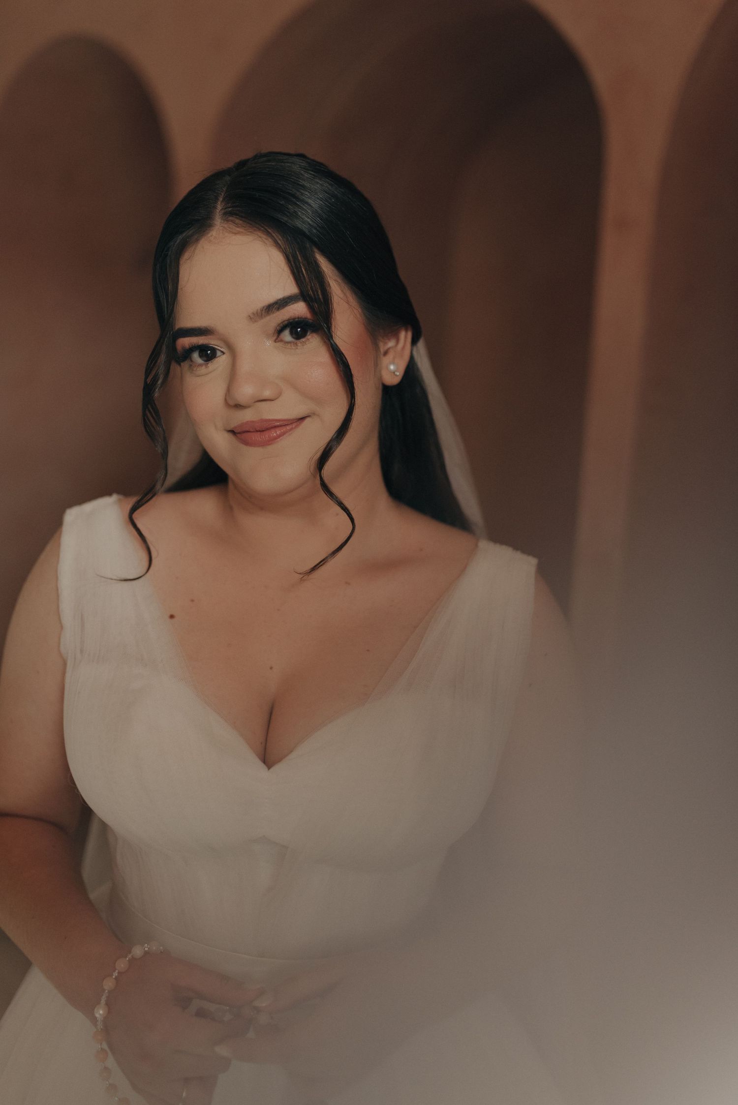 Warm-toned close-up portrait of a bride in a V-neck wedding dress.