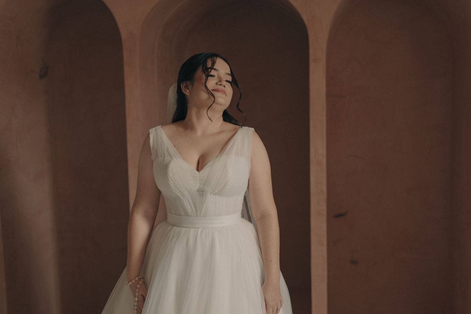 Elegant bridal portrait showing a classic white wedding gown against arched architecture.