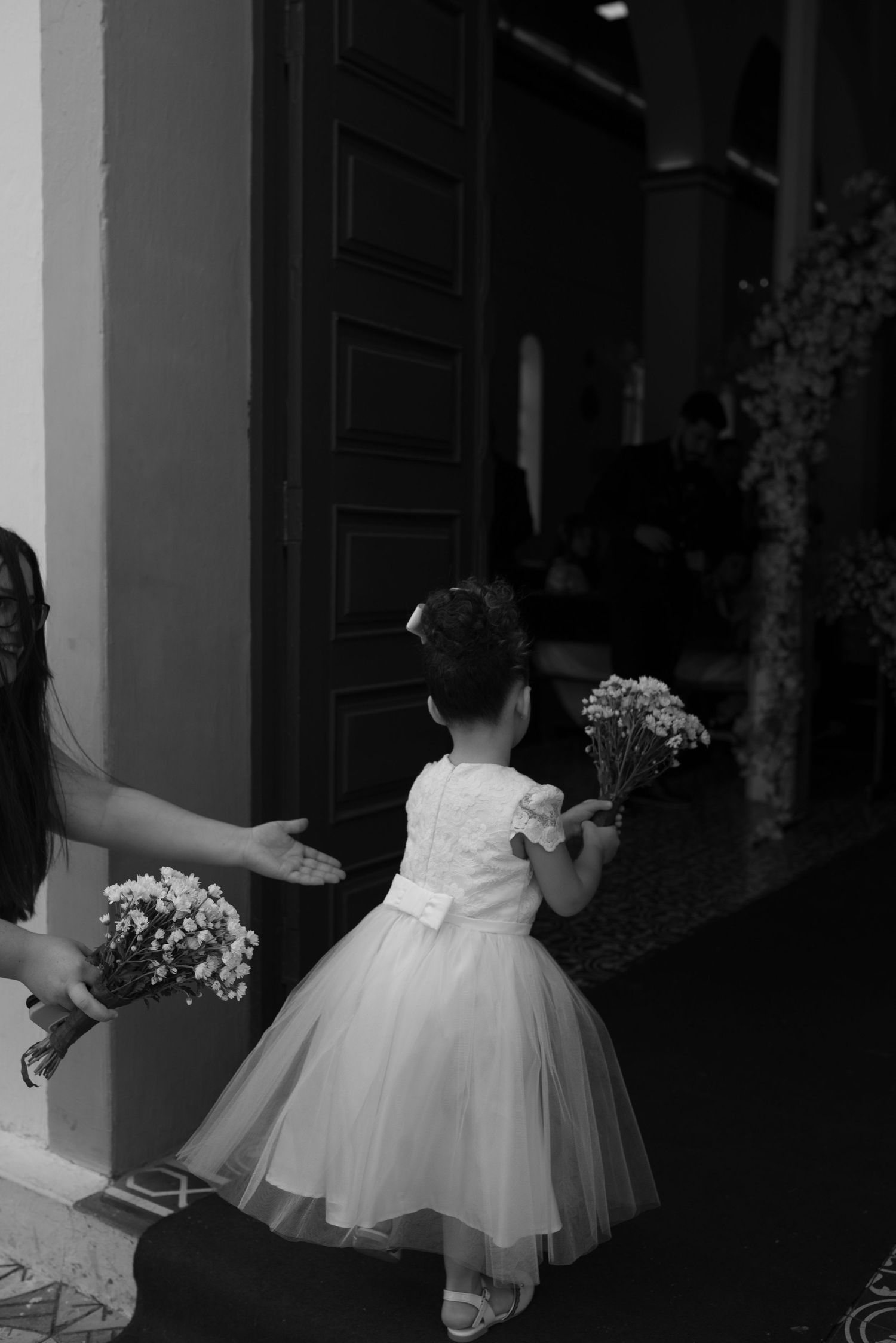 A small figure in a flowing white dress twirls on a patterned floor during a wedding celebration.