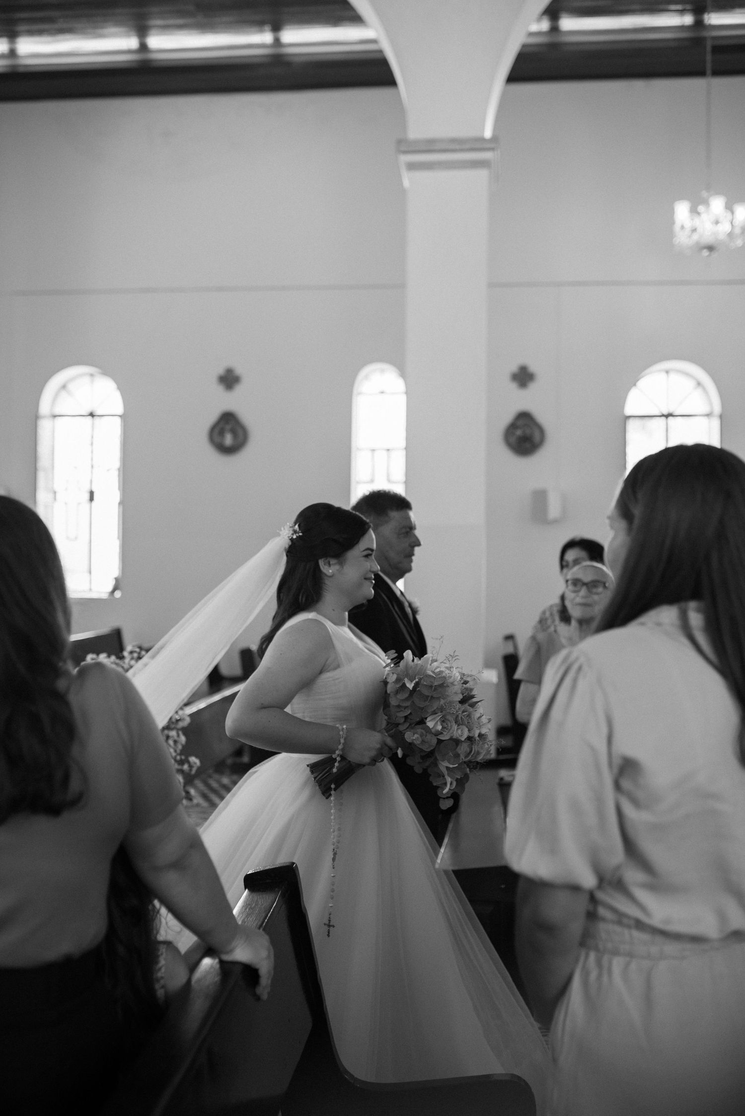 Elegant church wedding ceremony with guests gathered around a bride in a flowing white gown.