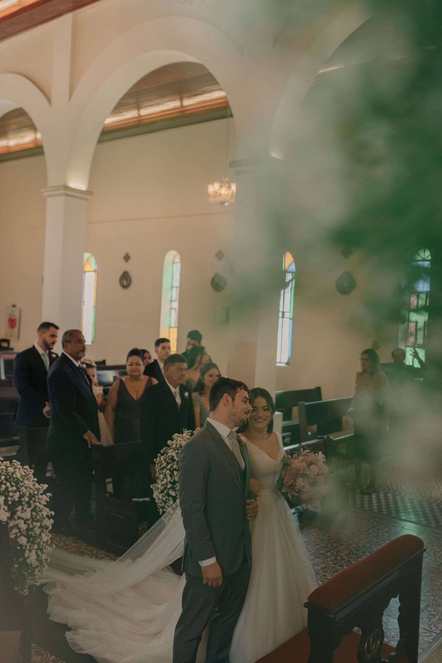 Wedding ceremony in progress inside an ornate church with white columns and stained glass windows.