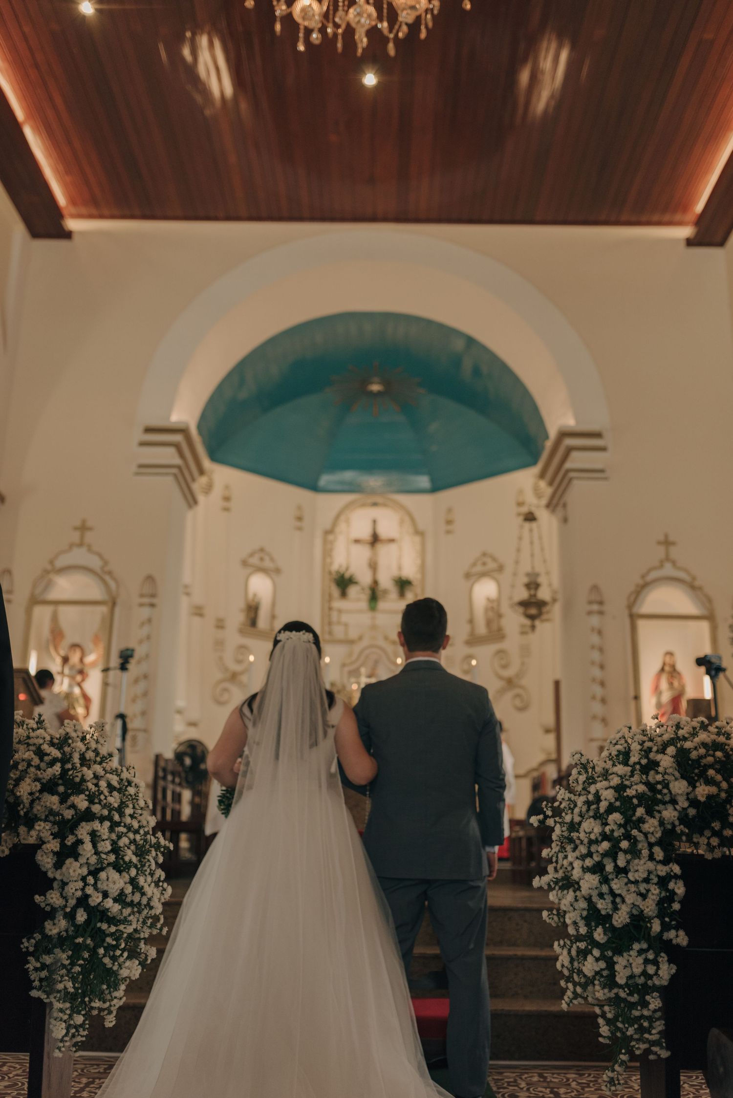 Wedding ceremony at altar with turquoise dome ceiling and white floral arrangements.