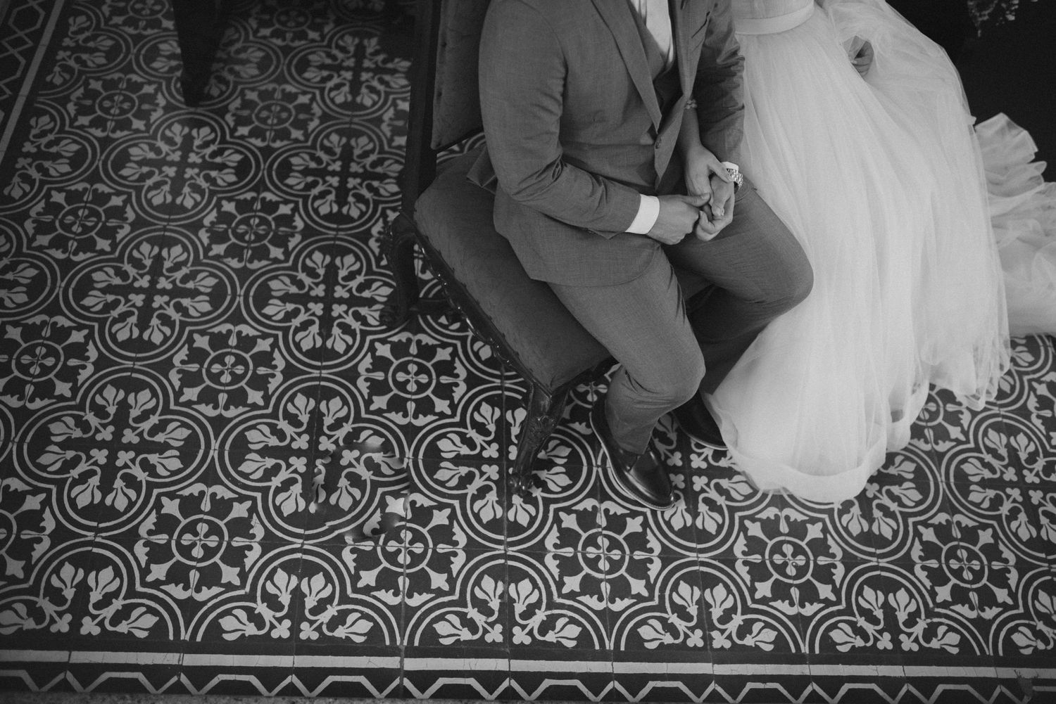 Black and white detail shot of ornate floor tiles with wedding dress fabric.