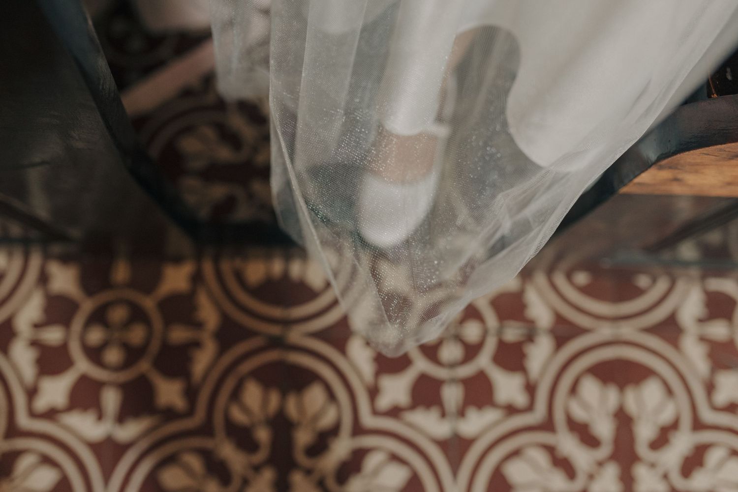 Close-up of wedding dress train on decorative tiled church floor.