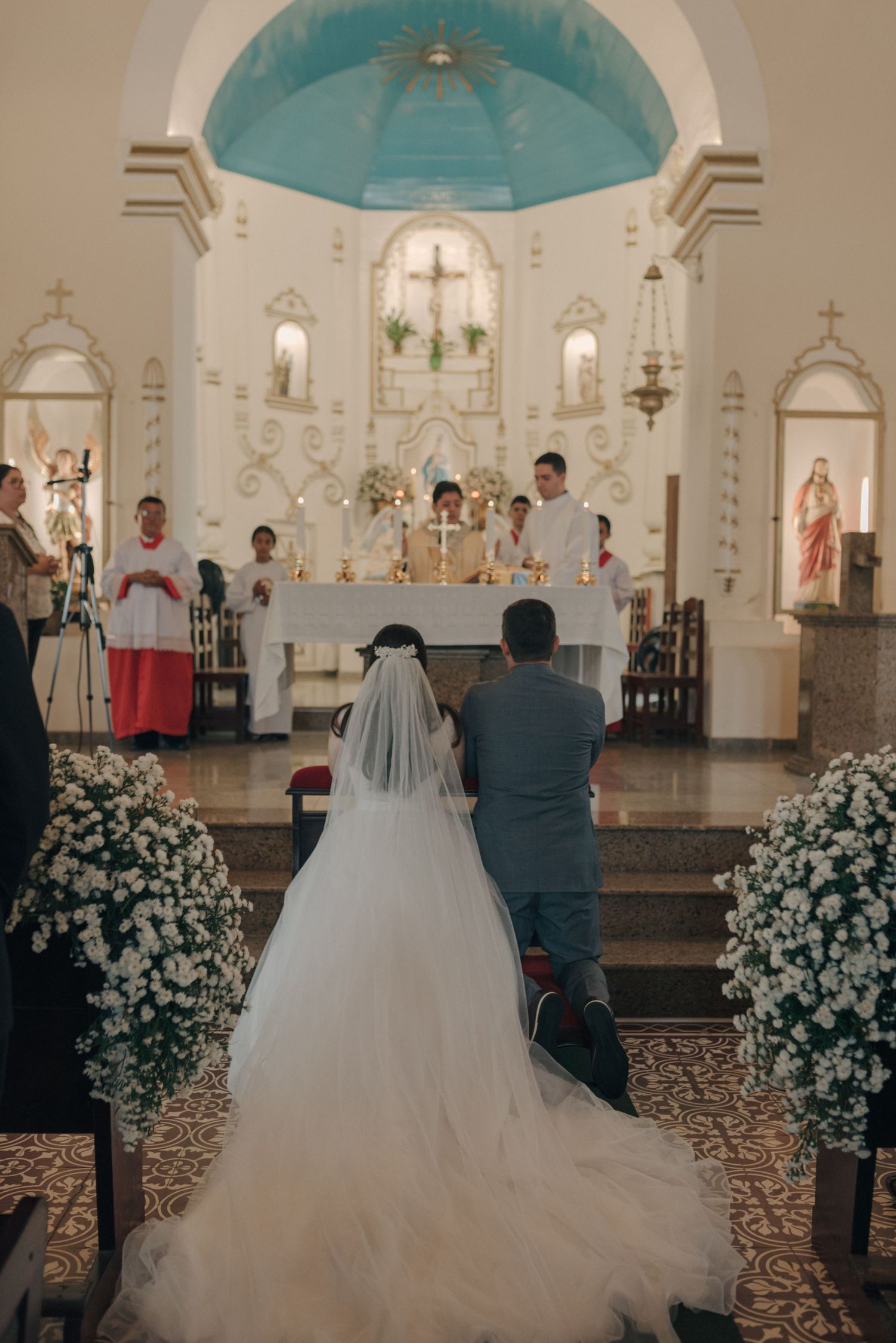 Catholic wedding ceremony with white floral arrangements and turquoise dome altar.