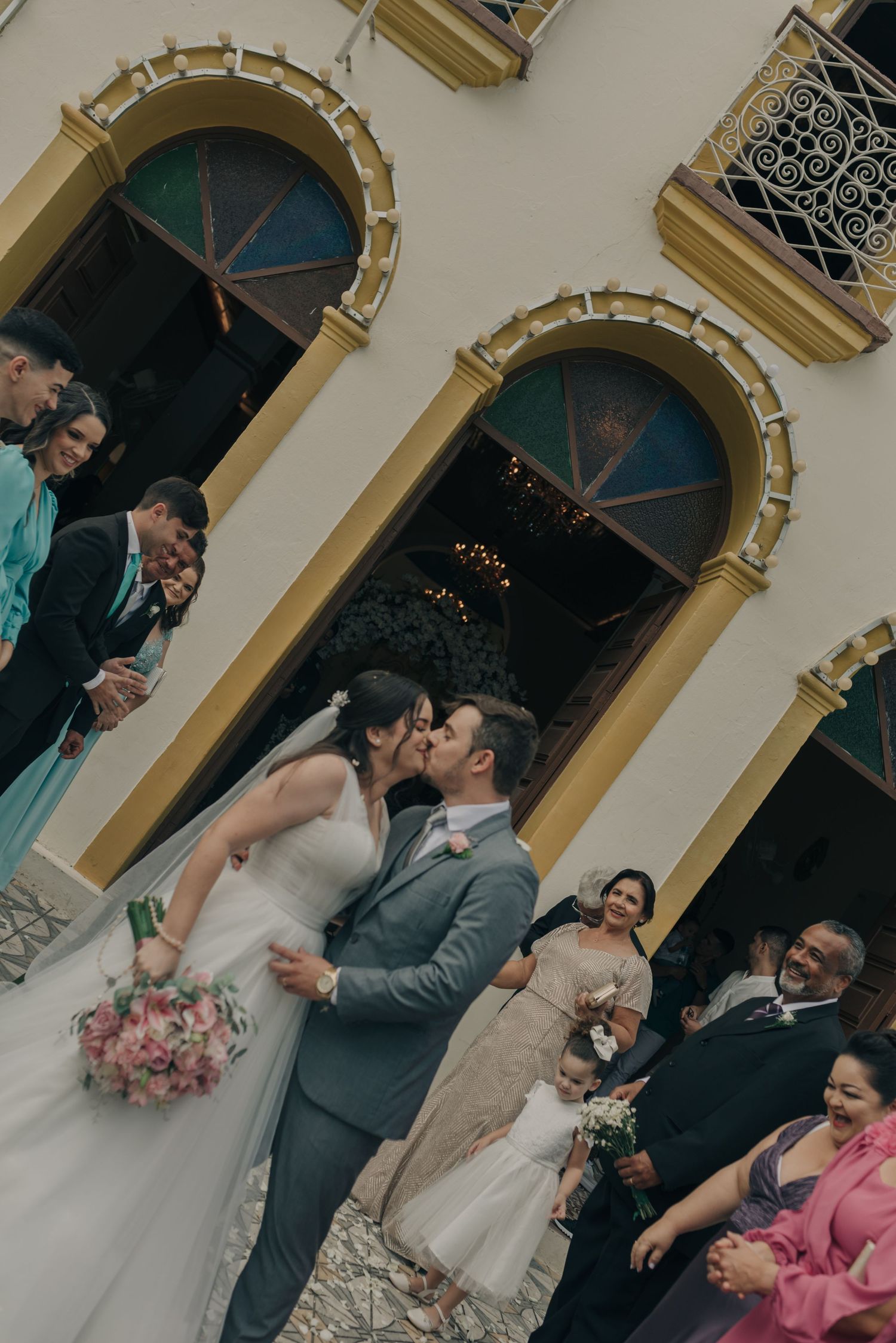 A romantic wedding moment surrounded by guests and arched architecture.
