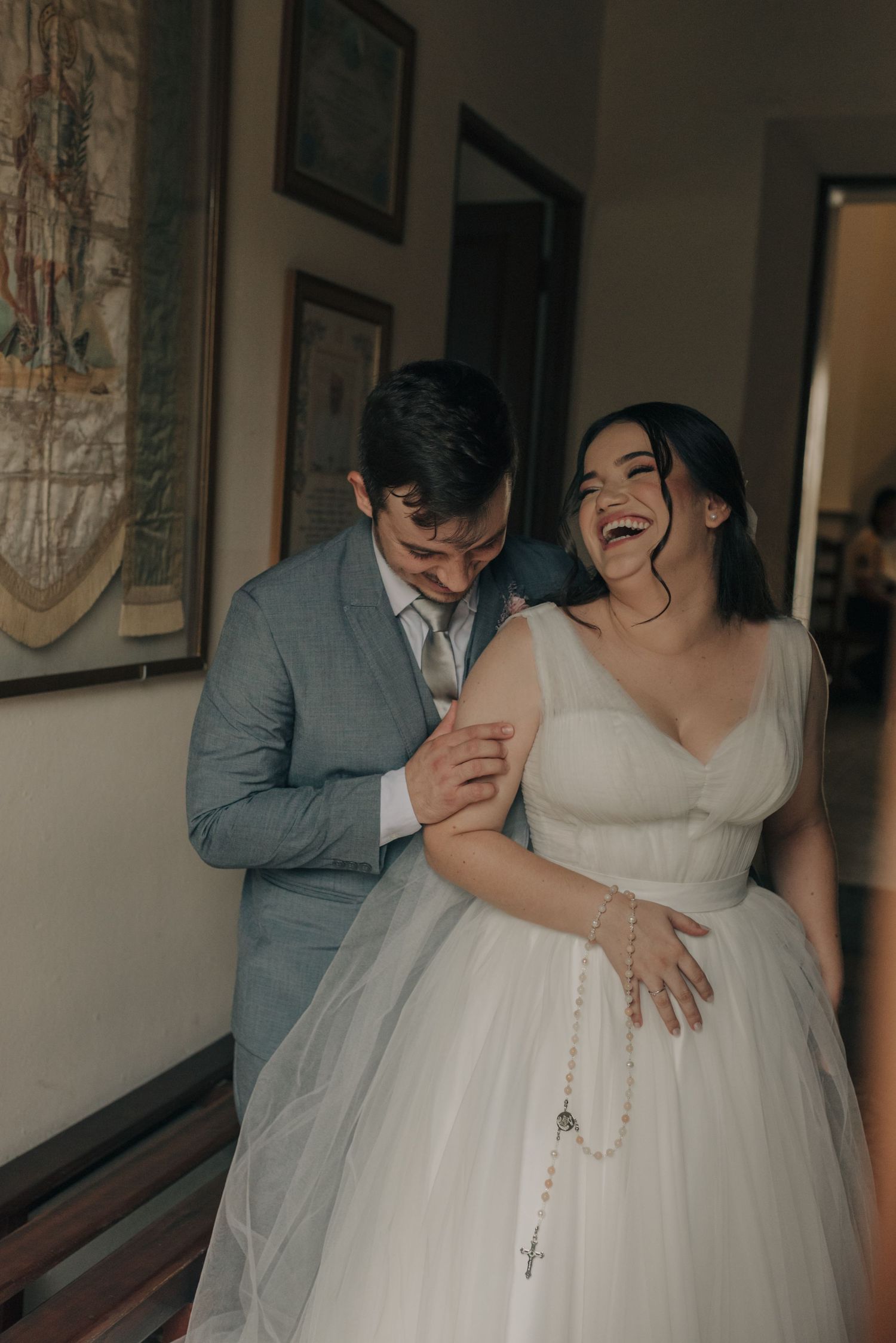 A joyful moment shared between newlyweds in a hallway with framed artwork.