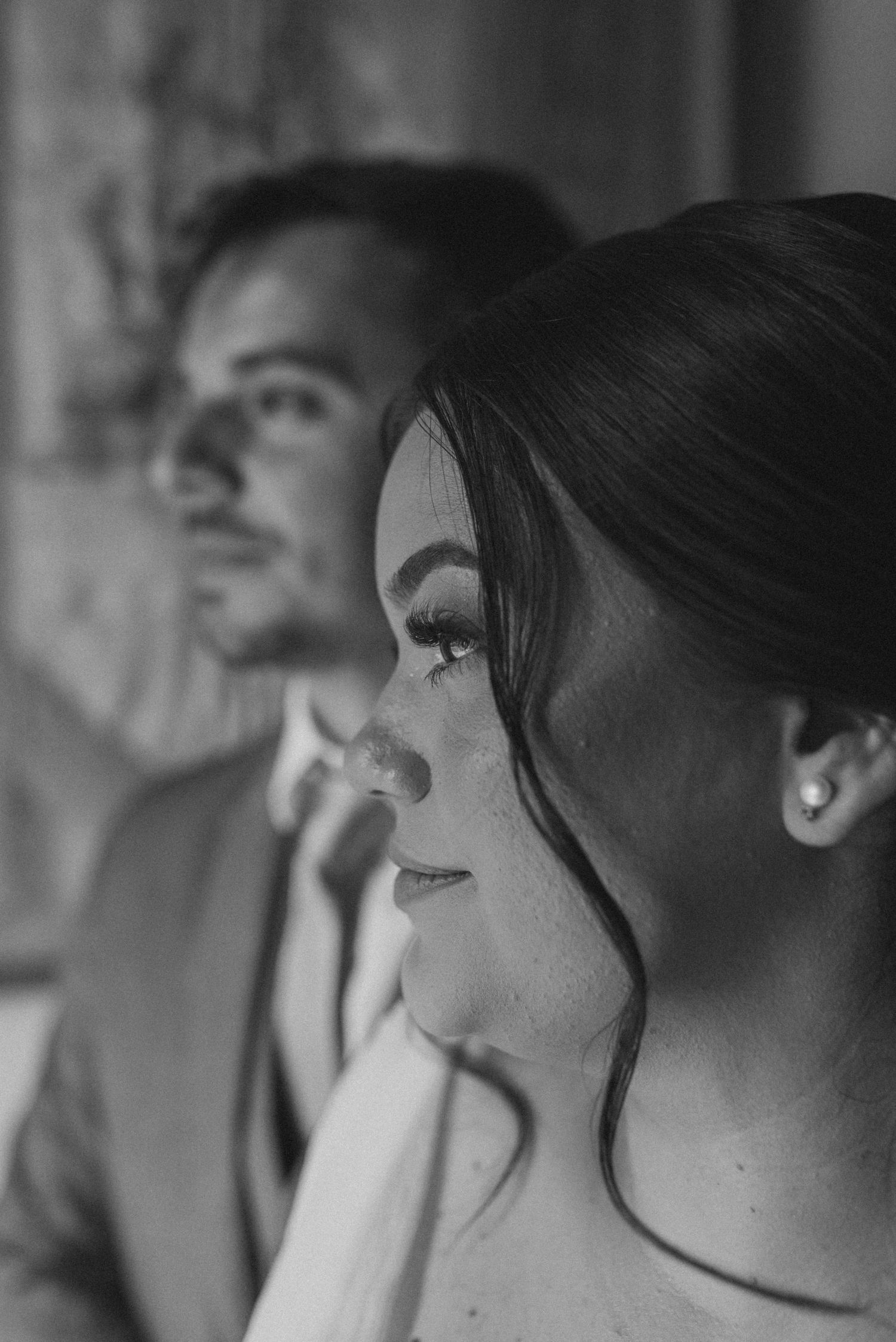 Black and white profile portrait of bride and groom side by side in soft lighting.