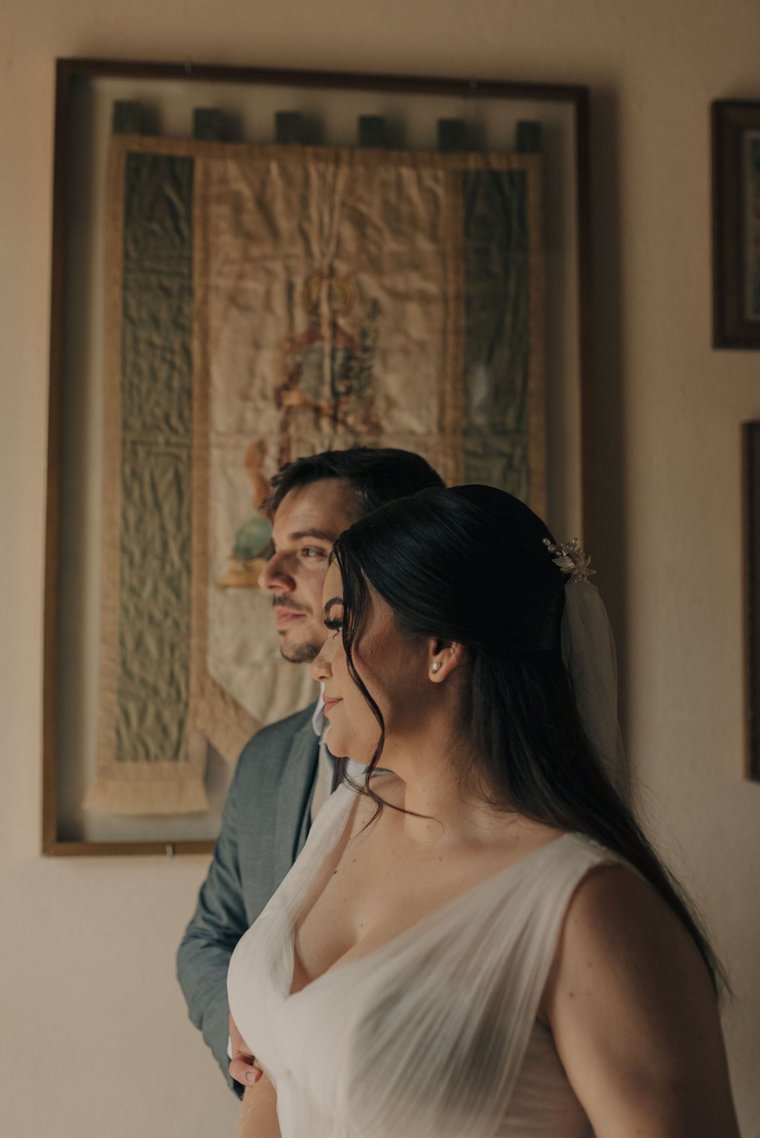 Intimate indoor portrait of couple in wedding attire looking away from camera.
